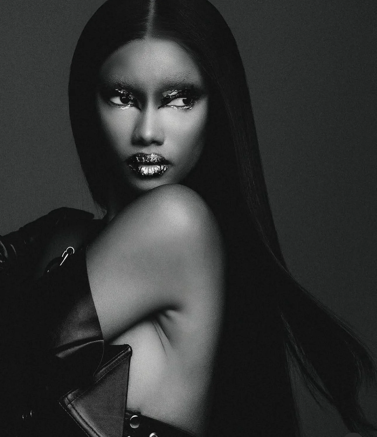 Black and white portrait of a woman with long straight hair, wearing a leather glove and jacket, with a serious expression, looking intensely at the camera.