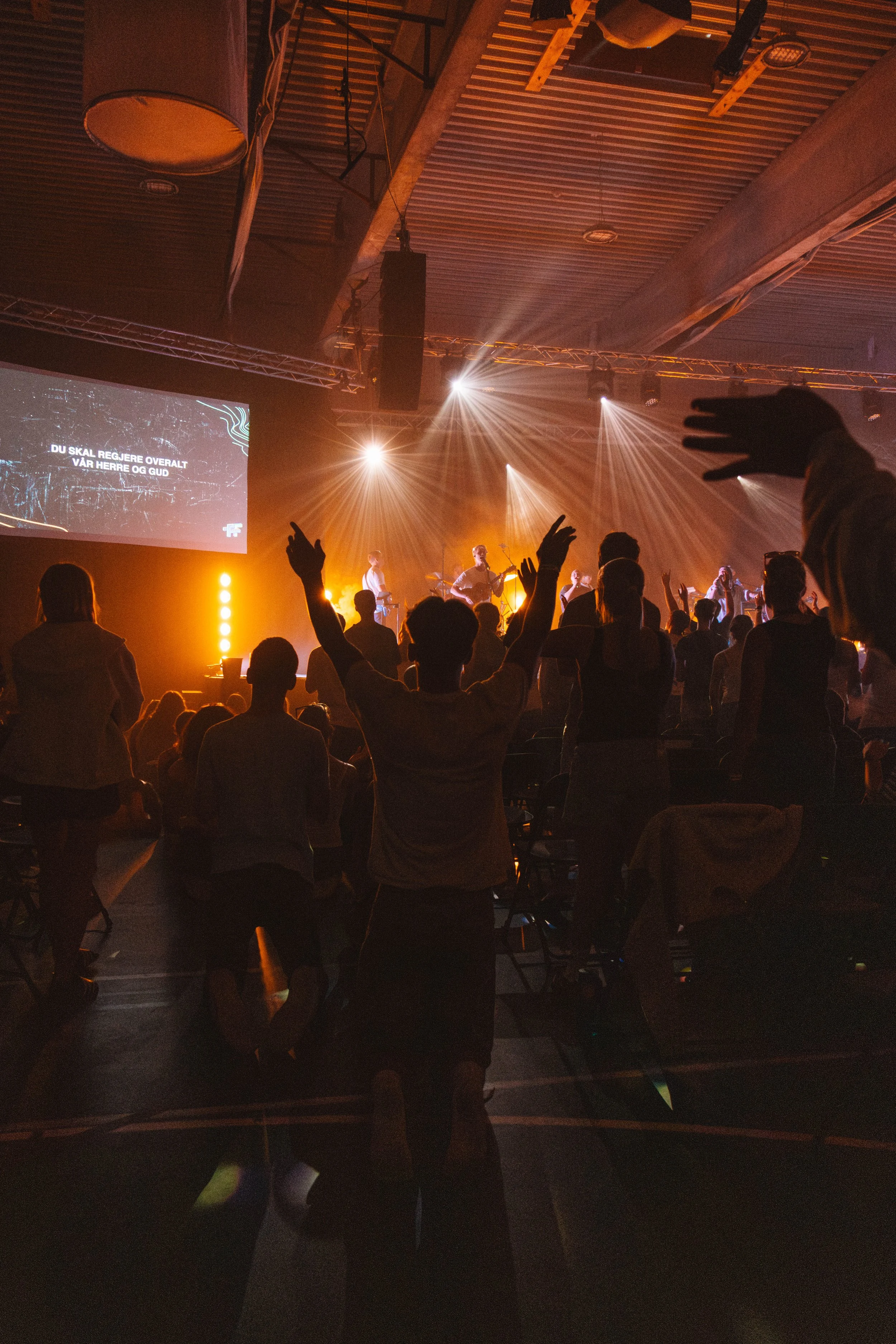 Konsert med folk som synger og danser, lyssetting, scenebilde.
