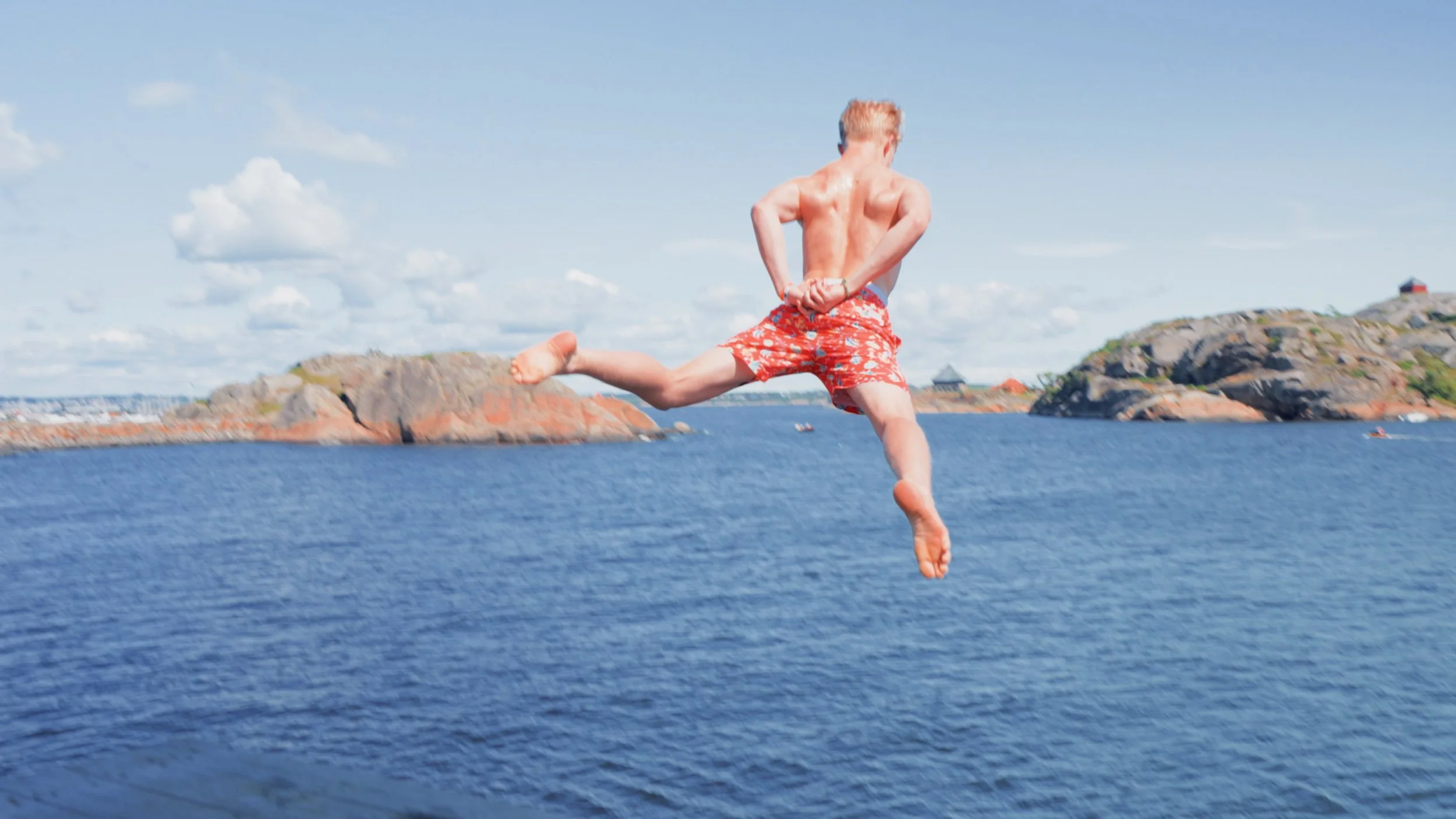 Ungdom som stuper ut i sjøen på en varm sommerdag