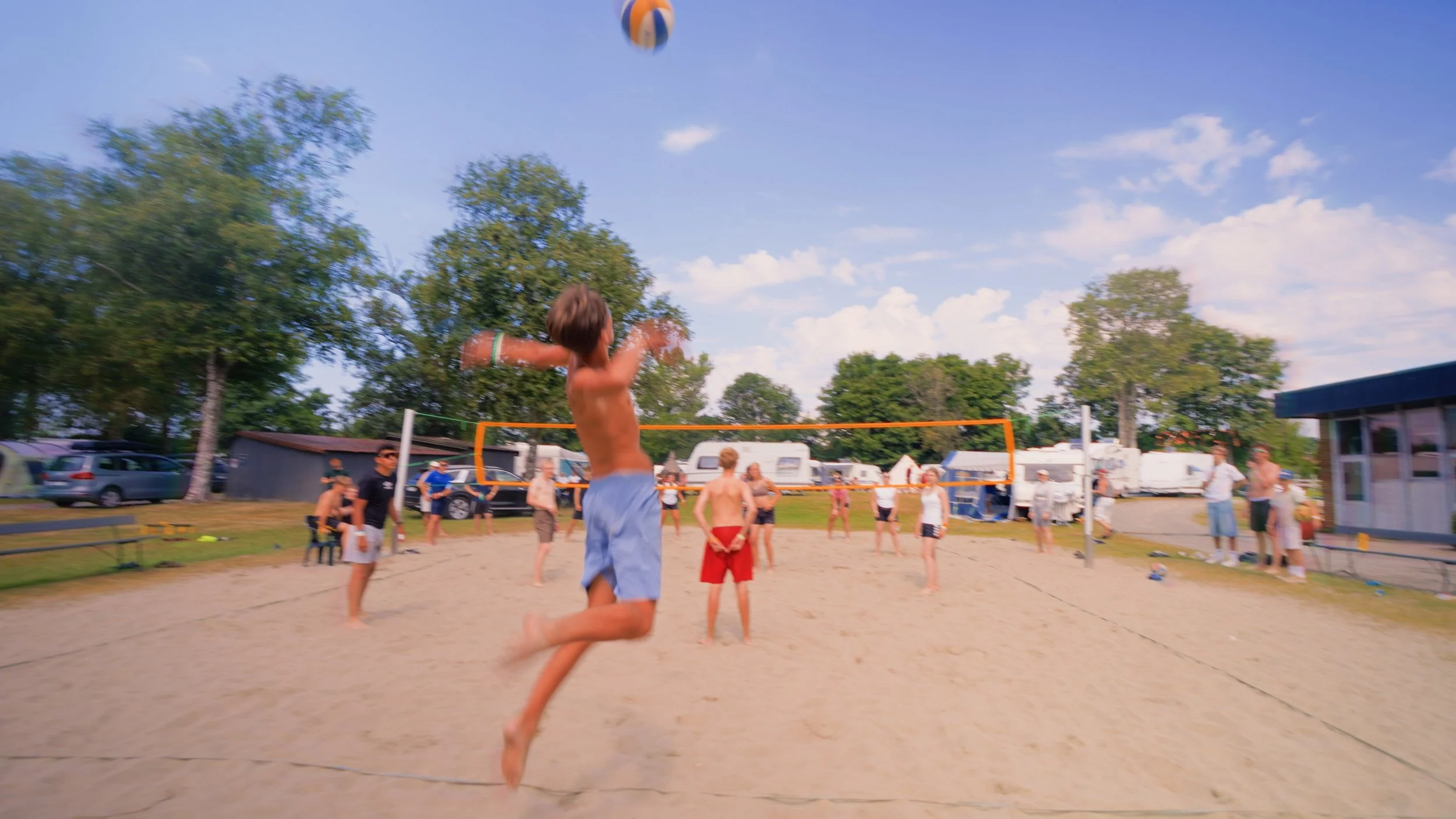 Ungdom som spiller volleyball på Frikfestivalen sine områder,, under en blå himmel.