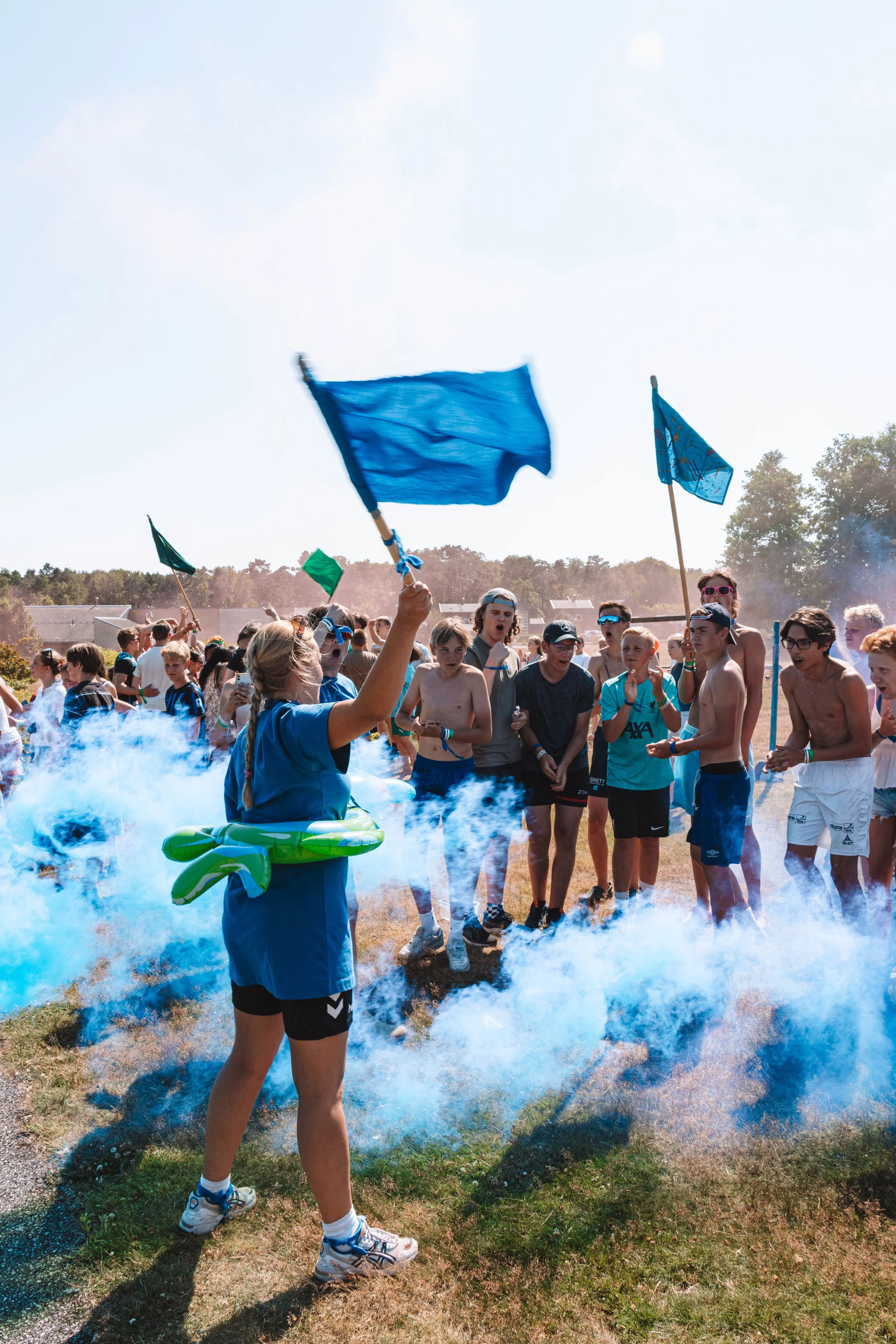 En stor gjeng som deltar i "mesterens mester". Team blå har nettopp vunnet, og flaggene er hevet, og blå røyk dekker området. Det er god stemning