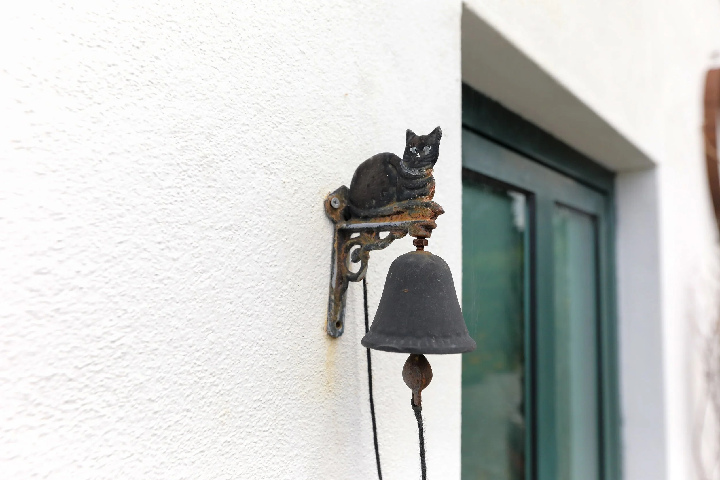 Sino de sino antigo com um gato de ferro em cima da estrutura, ao lado de uma janela de vidro