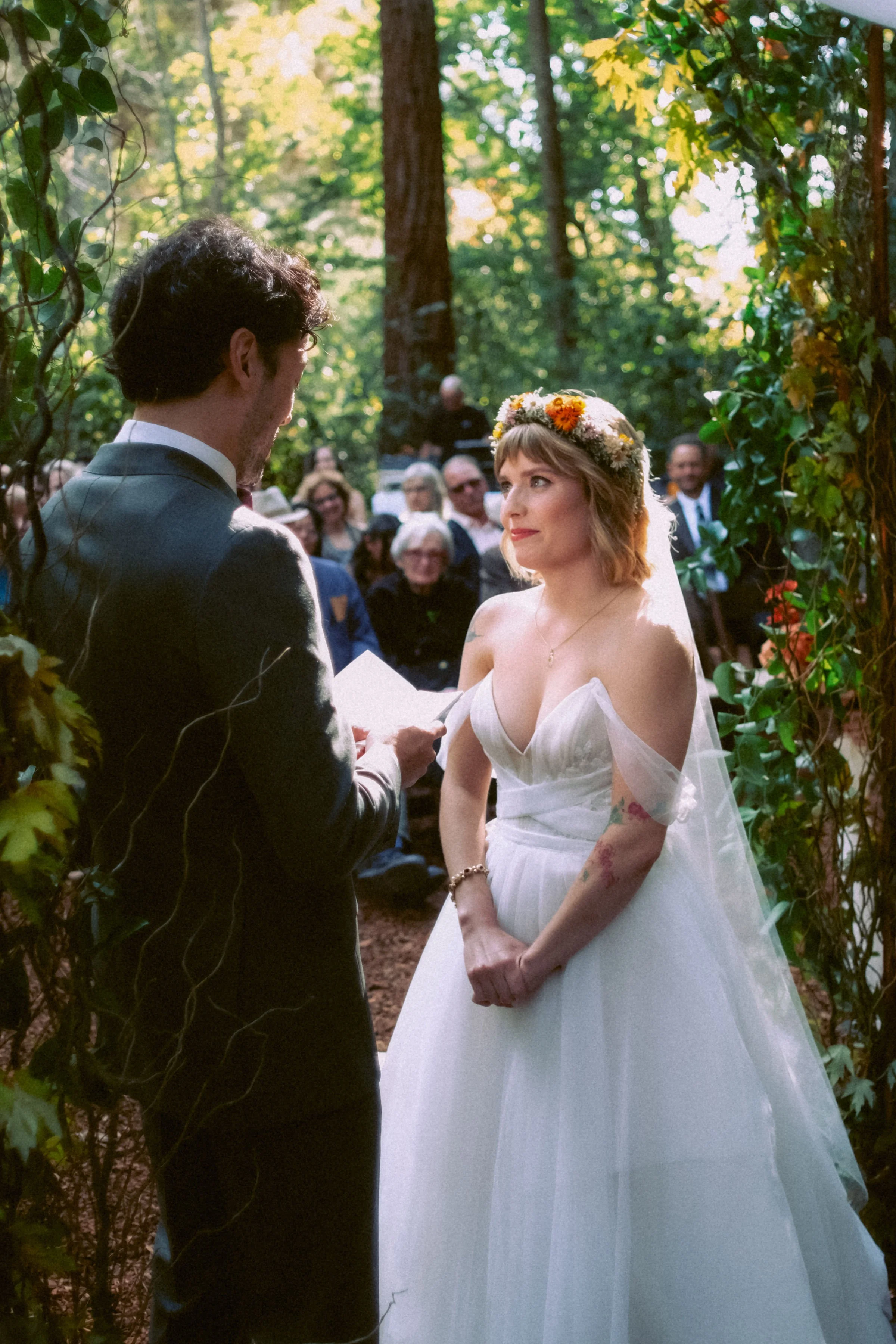 A bride and groom exchanging vows during an outdoor wedding ceremony in a wooded area.