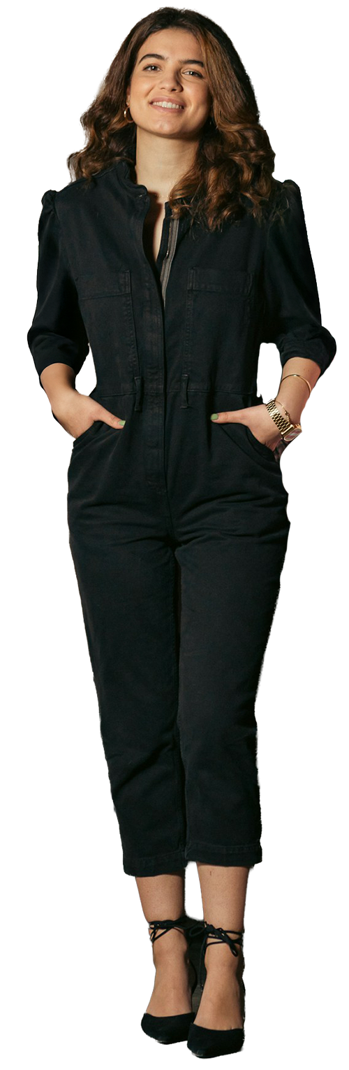 latina woman looking at camera with hands in her pockets, wearing a full body suit and jewelry