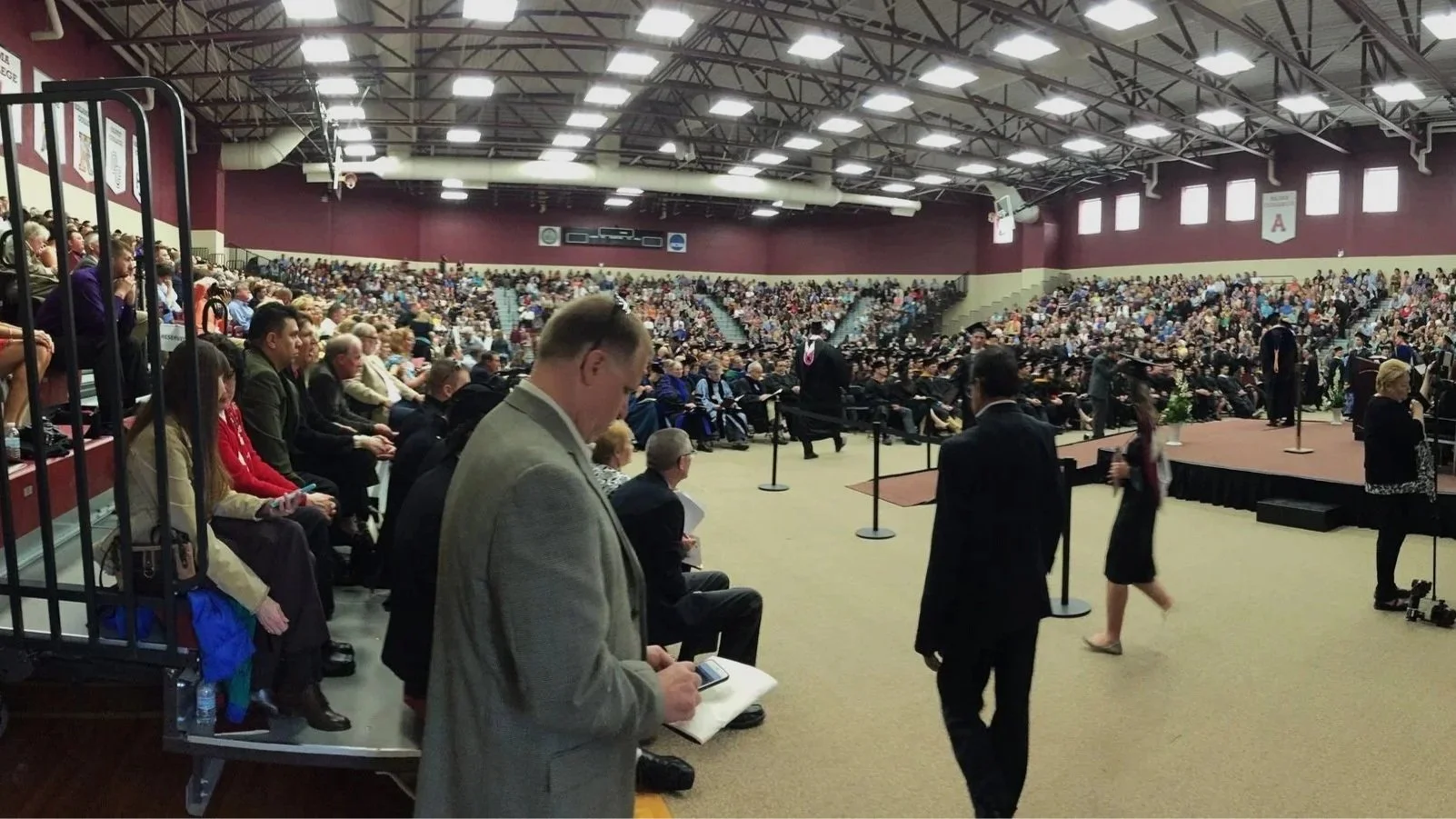 Alma College indoor graduation ceremony in Art Smith Arena, attendees seated for event to start, audiovisual installation provided by OAV in arena for multifunctional events of ceremonies and sporting events.