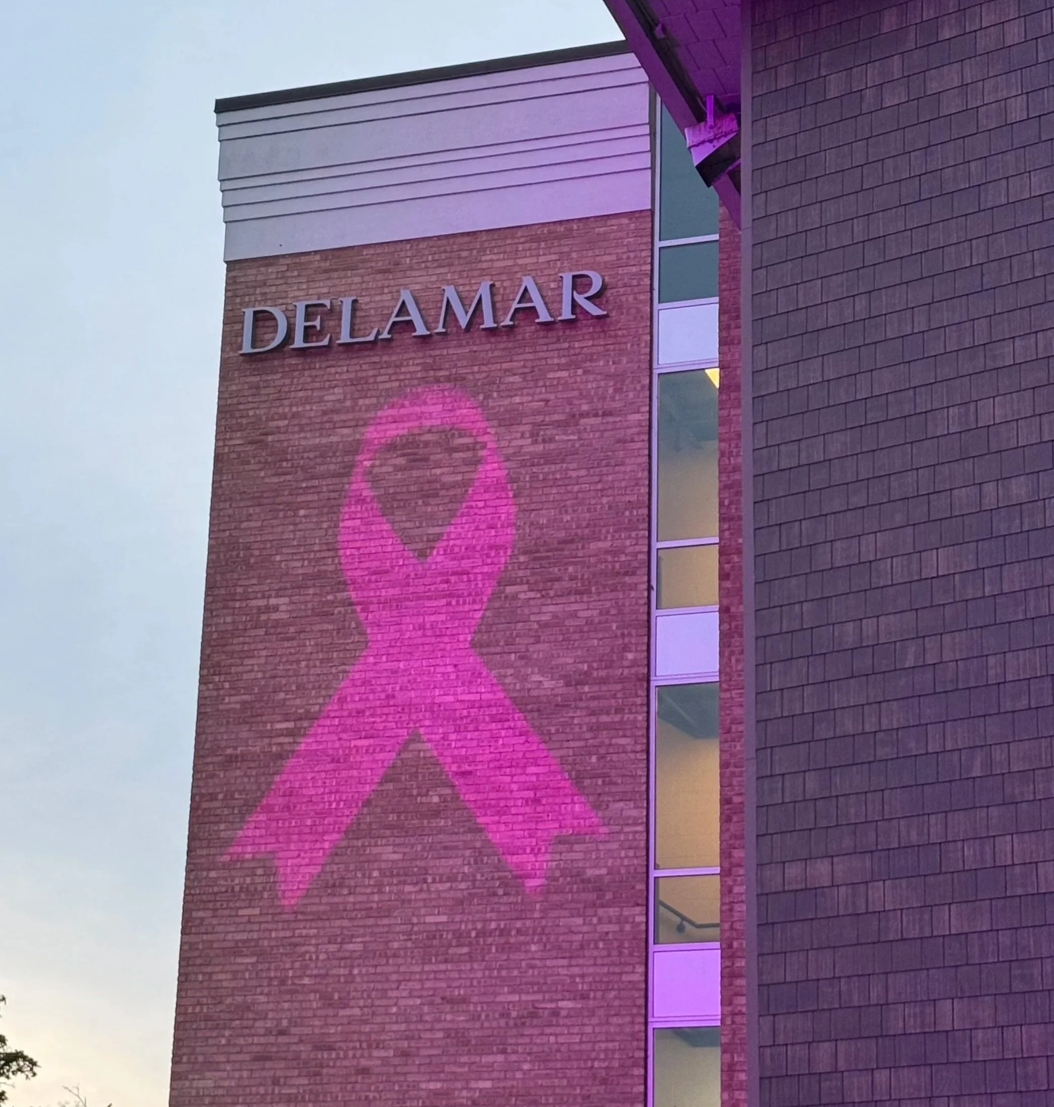 Delamar Hotel in Traverse City, exterior lighting projection of breast cancer pink ribbon for Raise a Rose event, Bon Jovi sponsored. Gobo lens projecting any display onto historical and architectural features.