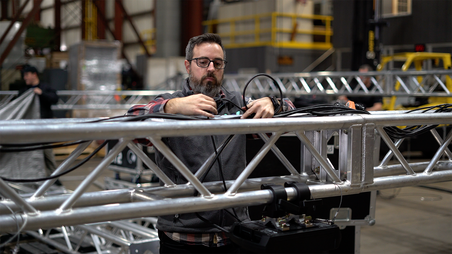 Audiovisual Project Manager working with martin lighting and video projection equipment on a metal truss in an industrial warehouse in Grand Rapids.