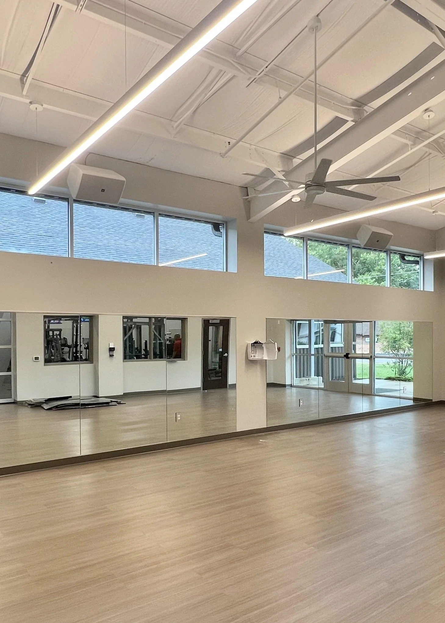 YMCA of Lowell Michigan fitness and gym studio with audiovisual installation components. Bright outdoor lighting, speakers hung from ceiling out of sight from those utilizing space, sound heard from all corners of the room.