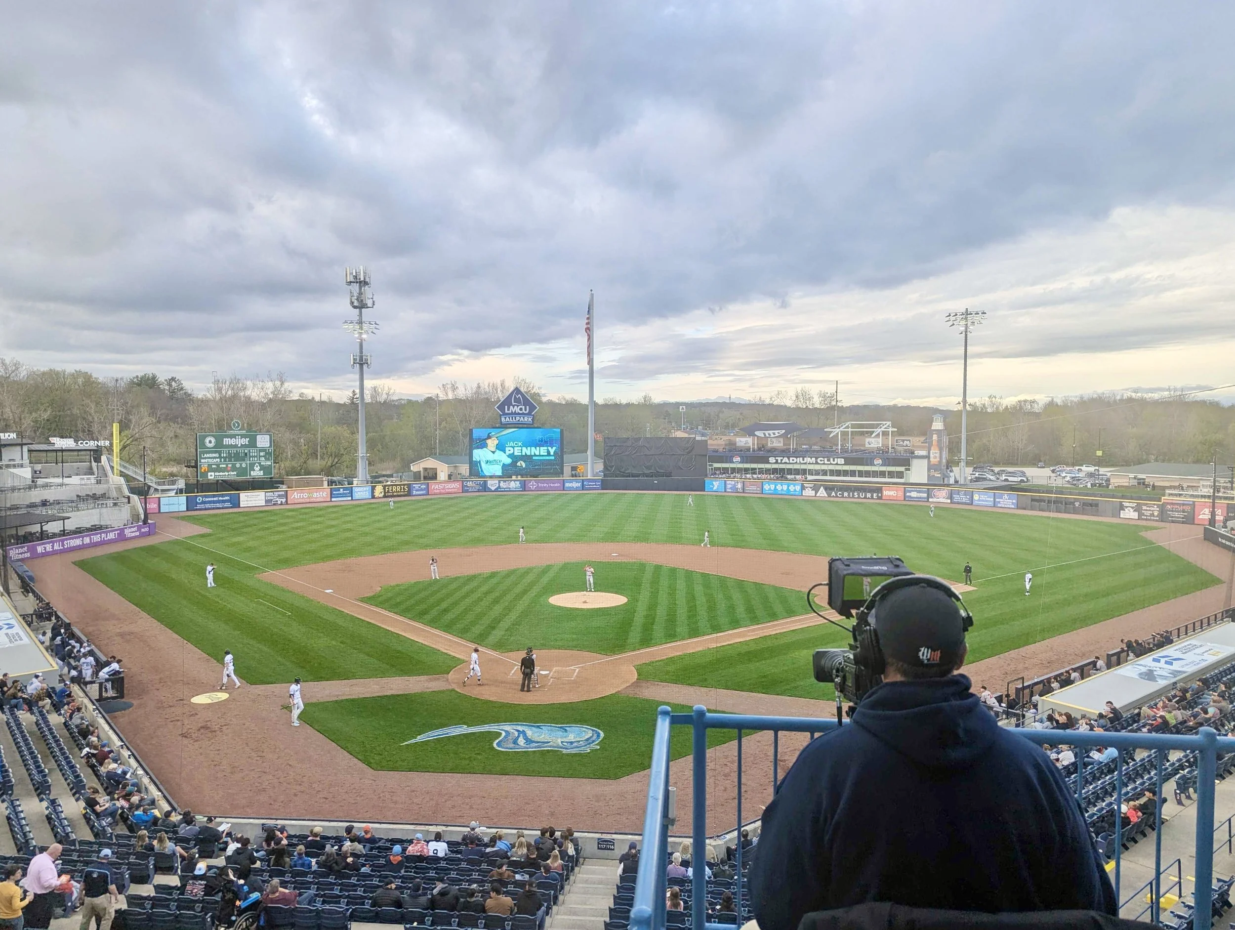 West Michigan Whitecaps baseball game in action, OAV providing managed AV through broadcast streaming services, stationairy camera operator with LED Video wall in background.