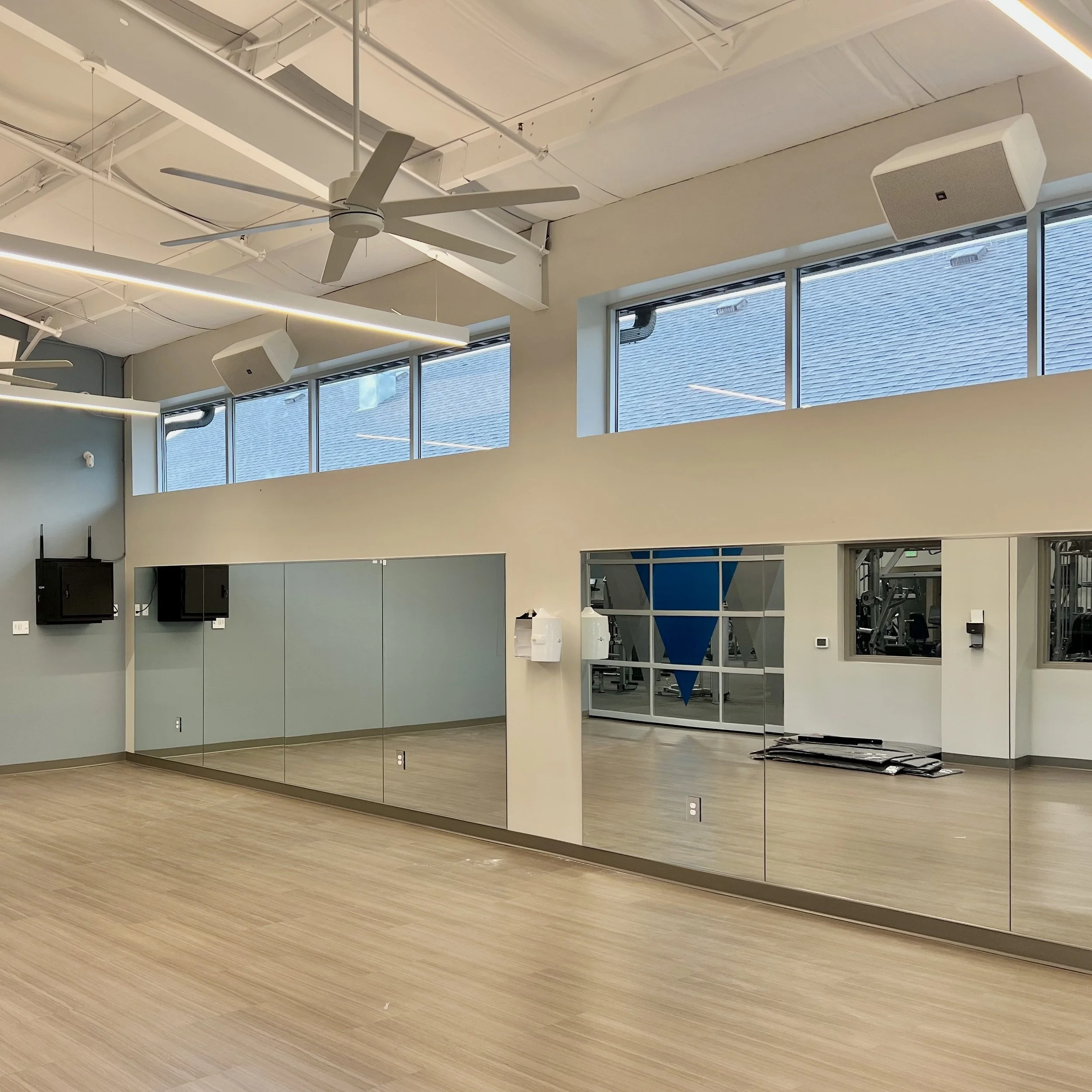 An indoor fitness studio with amplifiers out of view, JBL speakers flown on the ceiling, Harman Professional control on the wall, for an audiovisual installation to enhance fitness studios in Michigan.
