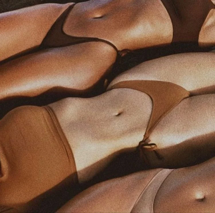 Close-up of three women lying on the floor wearing bikinis in black, brown, and beige colors.