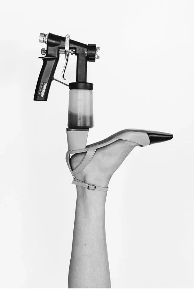 A human hand wearing a medical shoe, holding a tattoo machine, creating a mix of tattoo equipment and footwear.