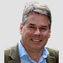 Photograph of a smiling middle-aged man with gray hair wearing a blue shirt and blazer