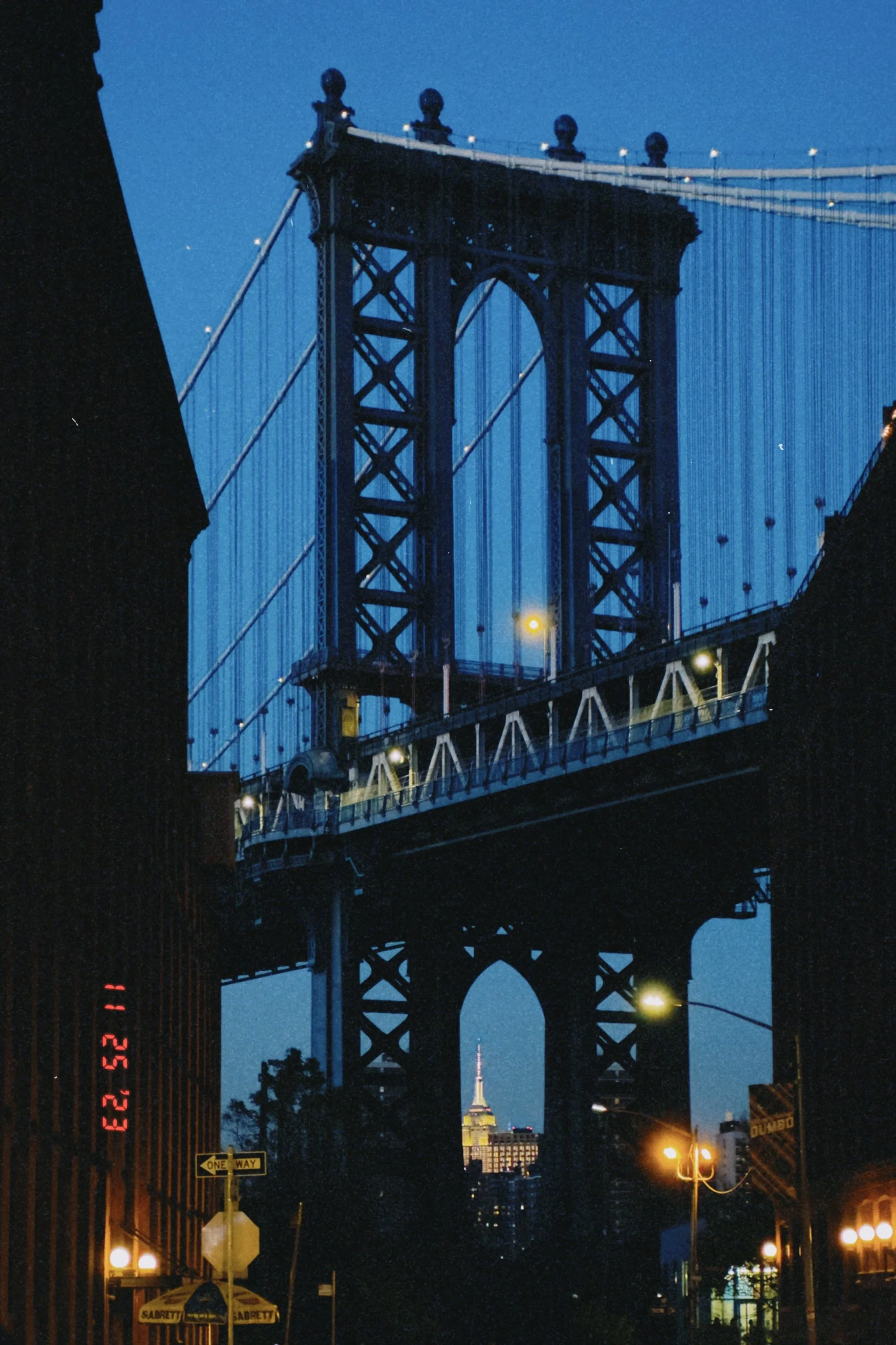 Photo of the Brooklyn Bridge at night with the Empire State Building visible in the background.