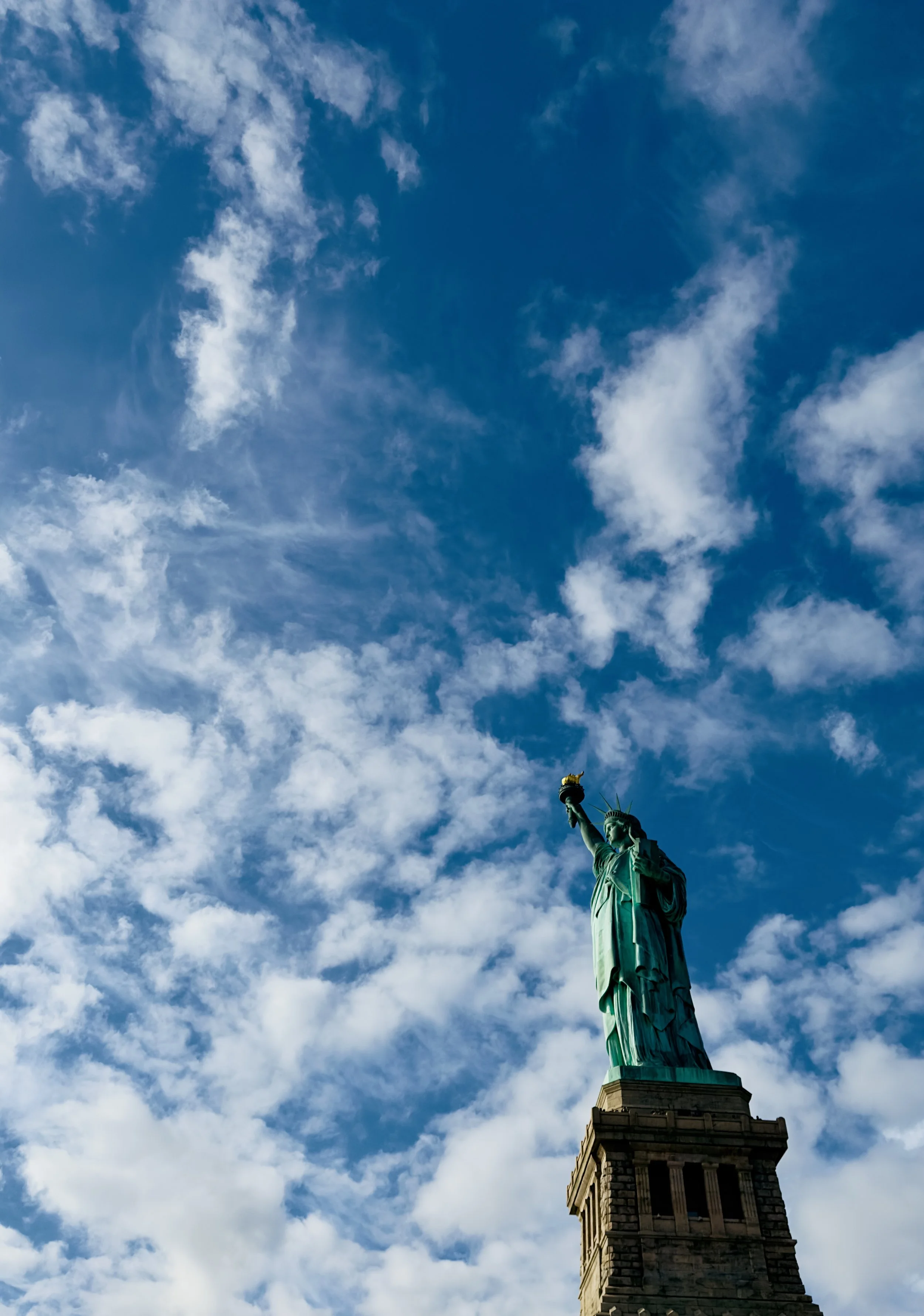 Statue of Liberty on a cloudy sky background.