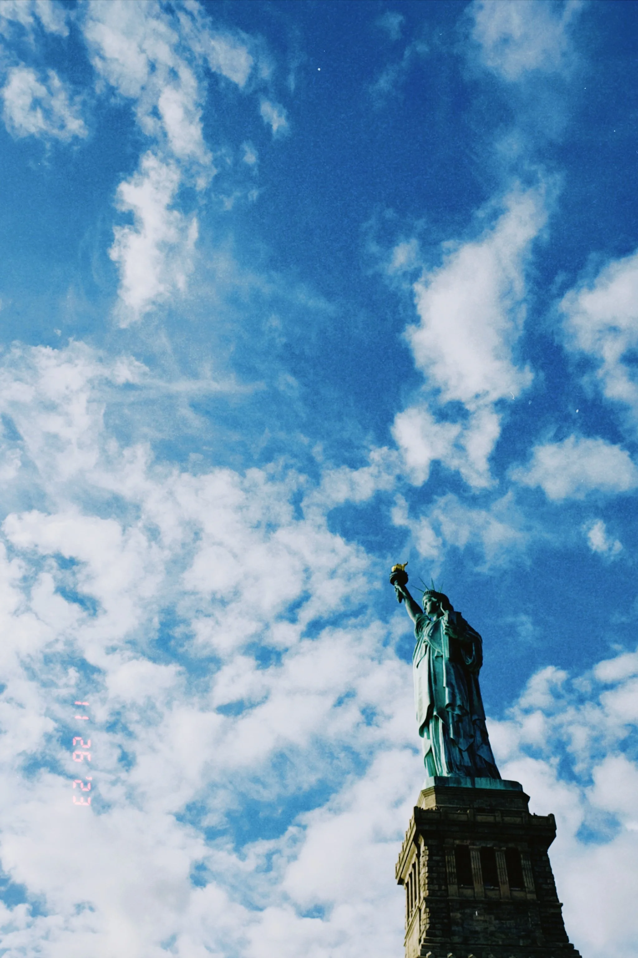 Statue of Liberty viewed from below against a partly cloudy sky.