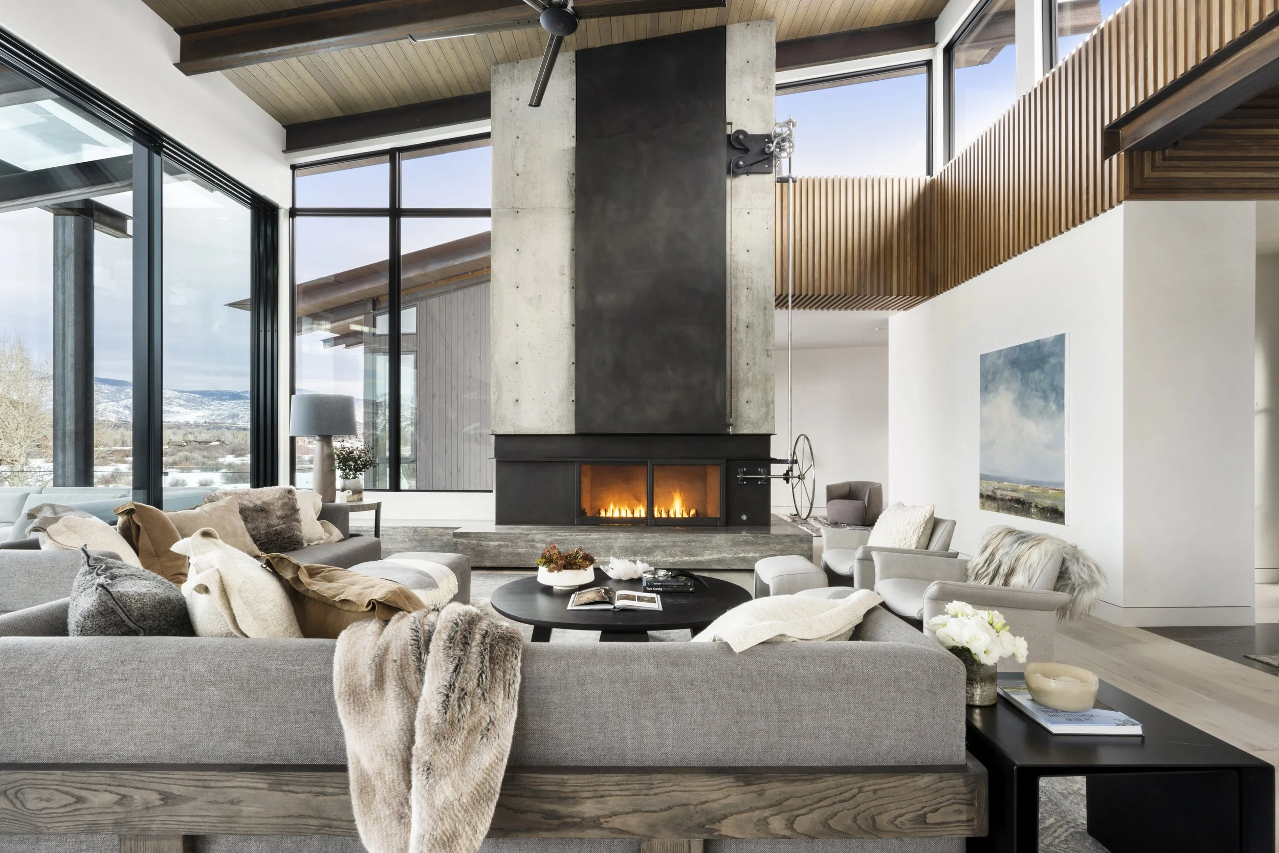 Modern living room with large windows, a fireplace, and contemporary furniture.