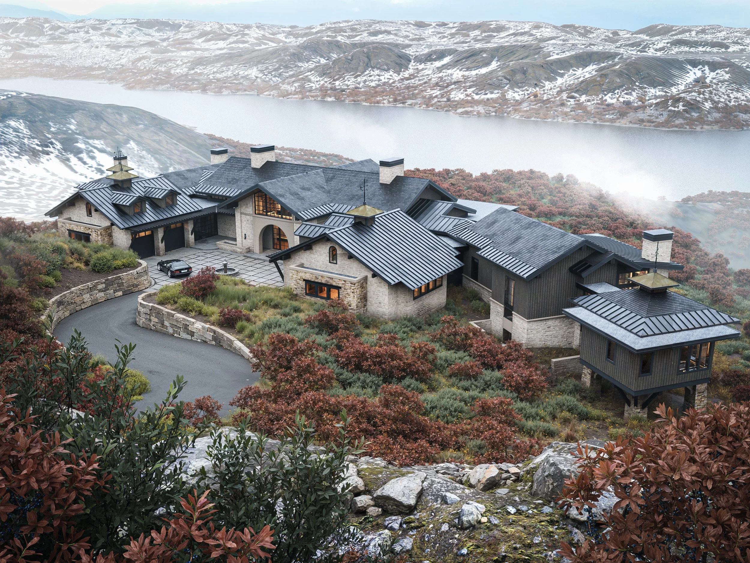 Luxury house on a hillside overlooking a lake surrounded by mountains and autumn foliage.
