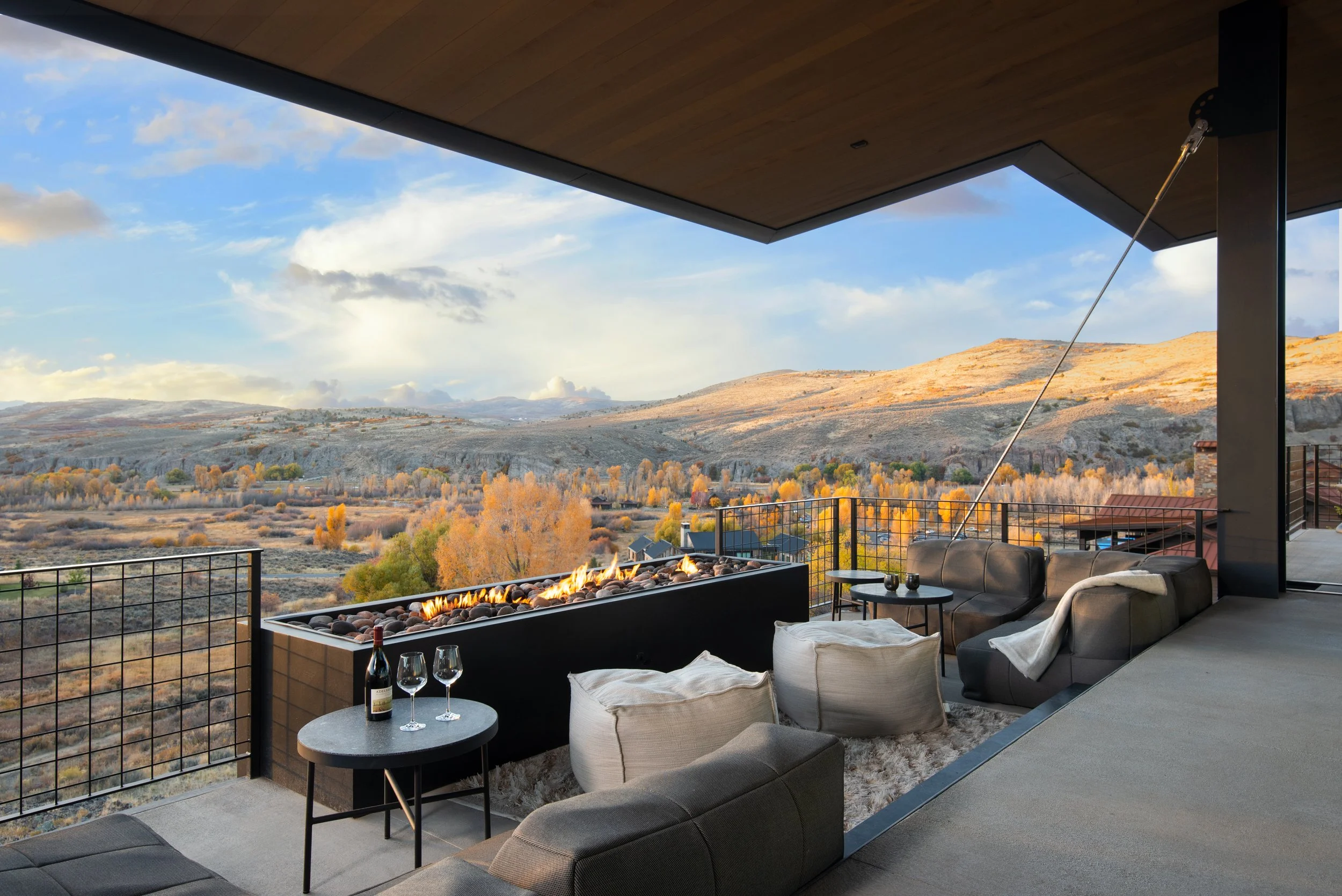 Outdoor patio with fireplace, seating area, and scenic mountain view with autumn trees.