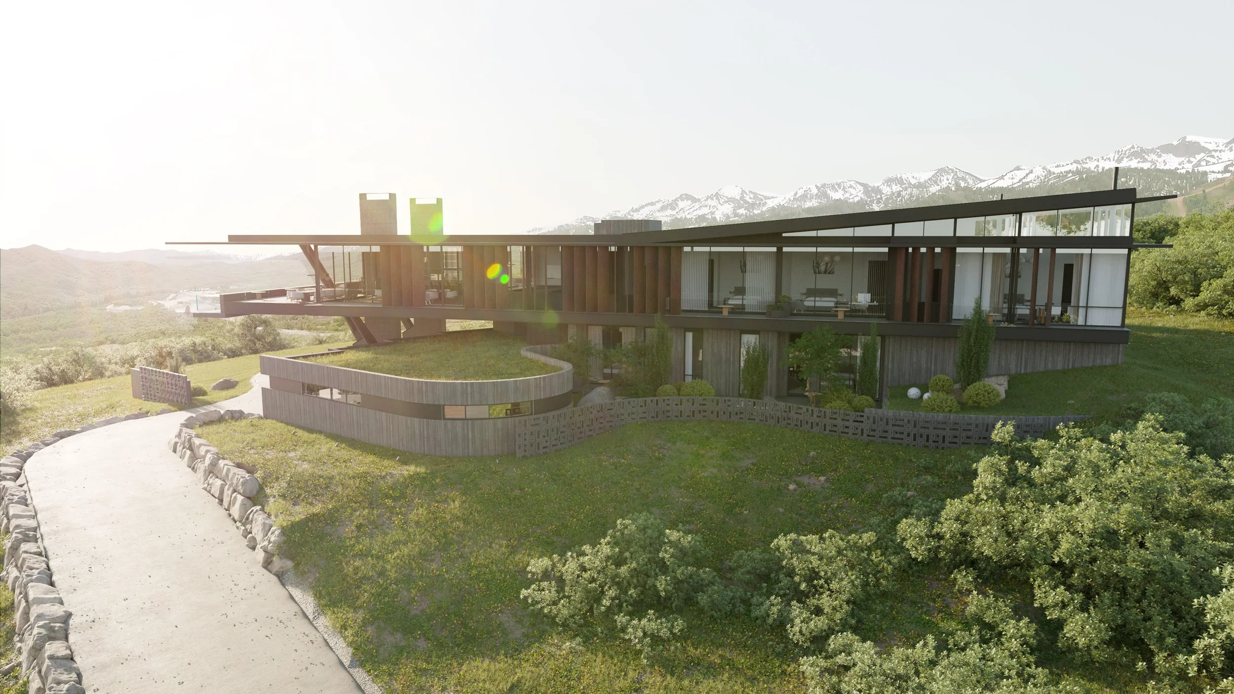 Modern house with large glass windows and a flat roof, situated on a grassy hillside with a mountain range in the background, under a bright sky.