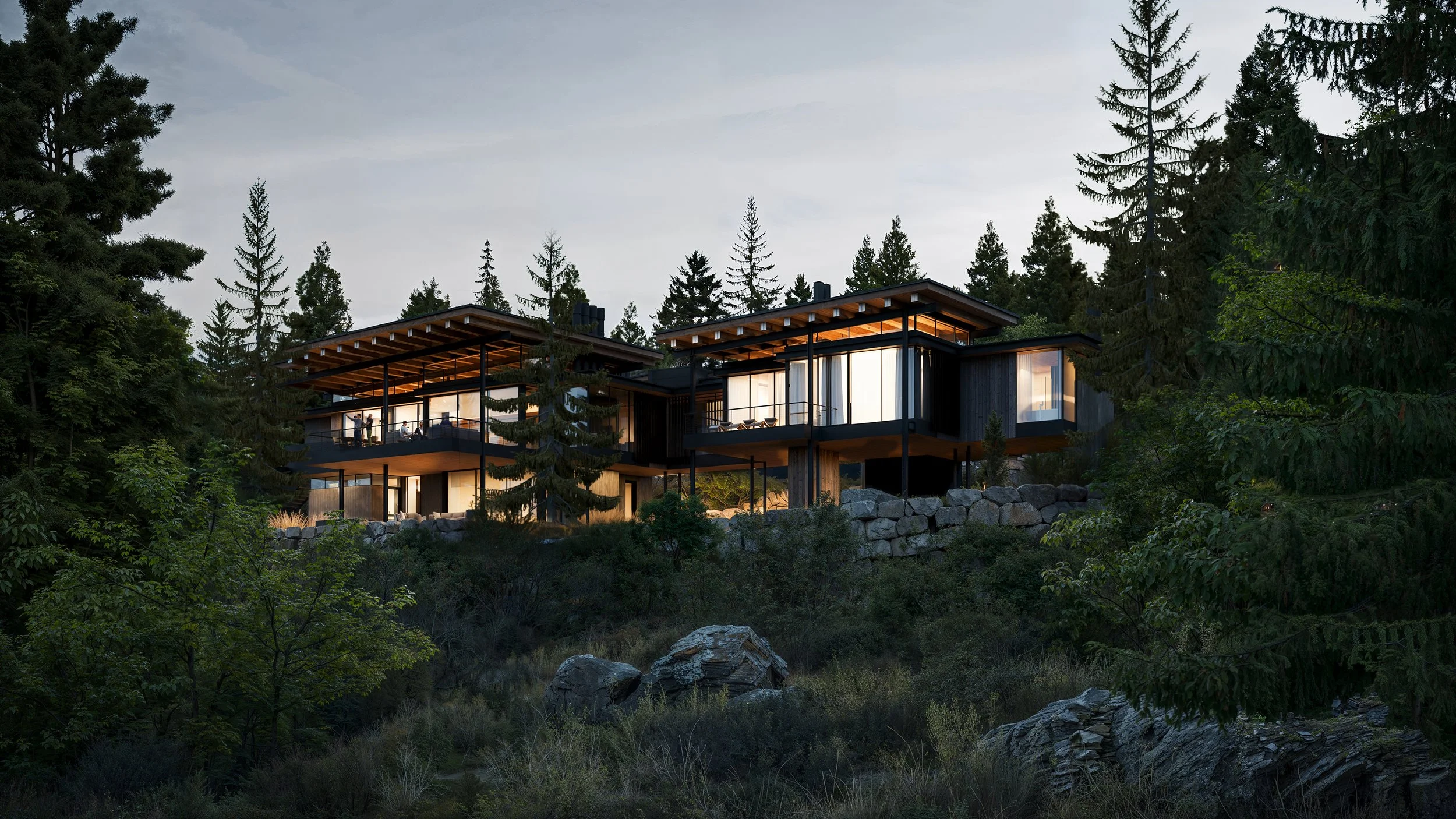 Modern house on a hillside surrounded by trees, with large windows and outdoor balconies, illuminated from within at dusk.
