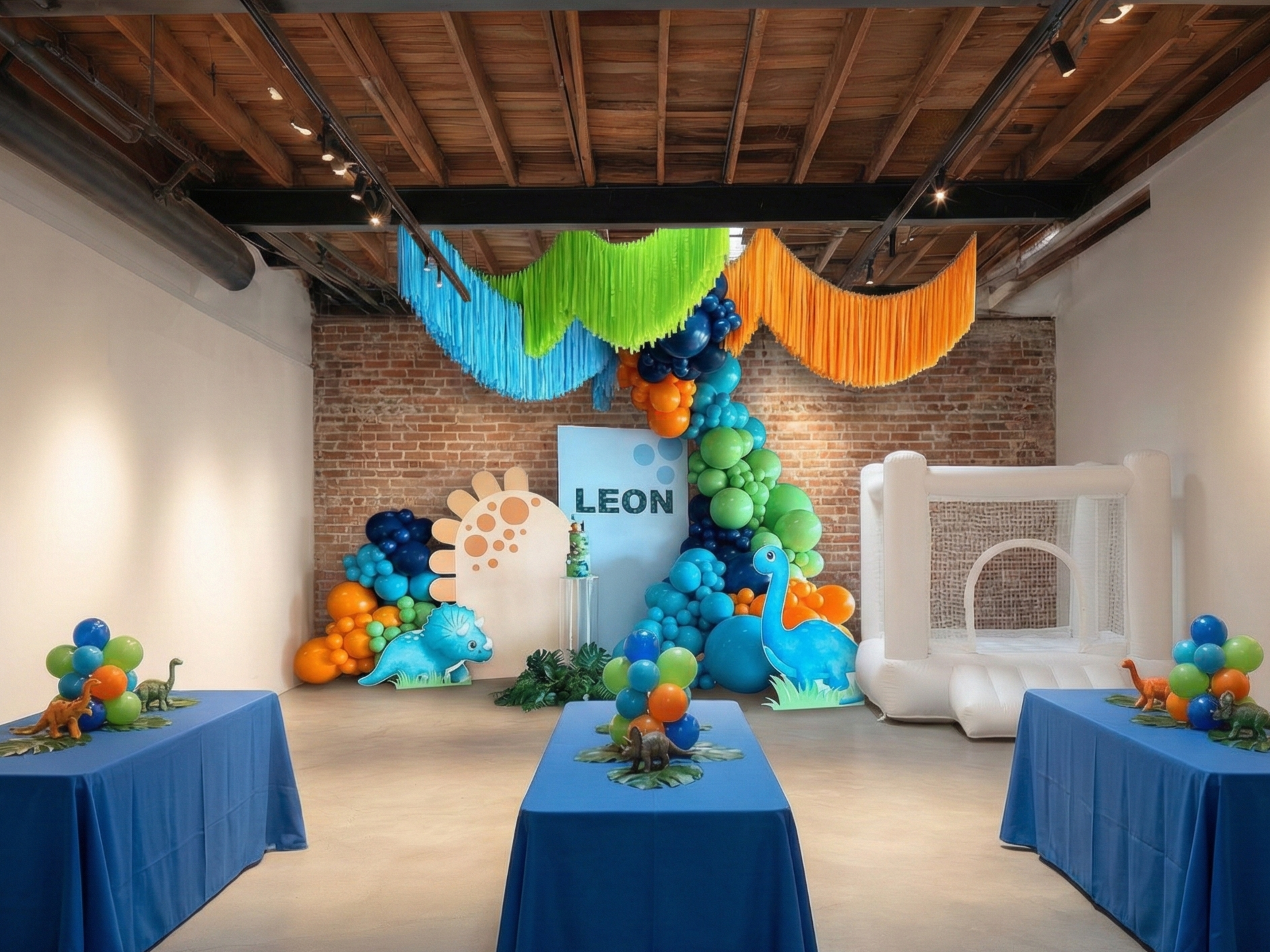 Baby dinosaur themed birthday party decorations with balloons, a bounce house, and a backdrop with the name Leon.