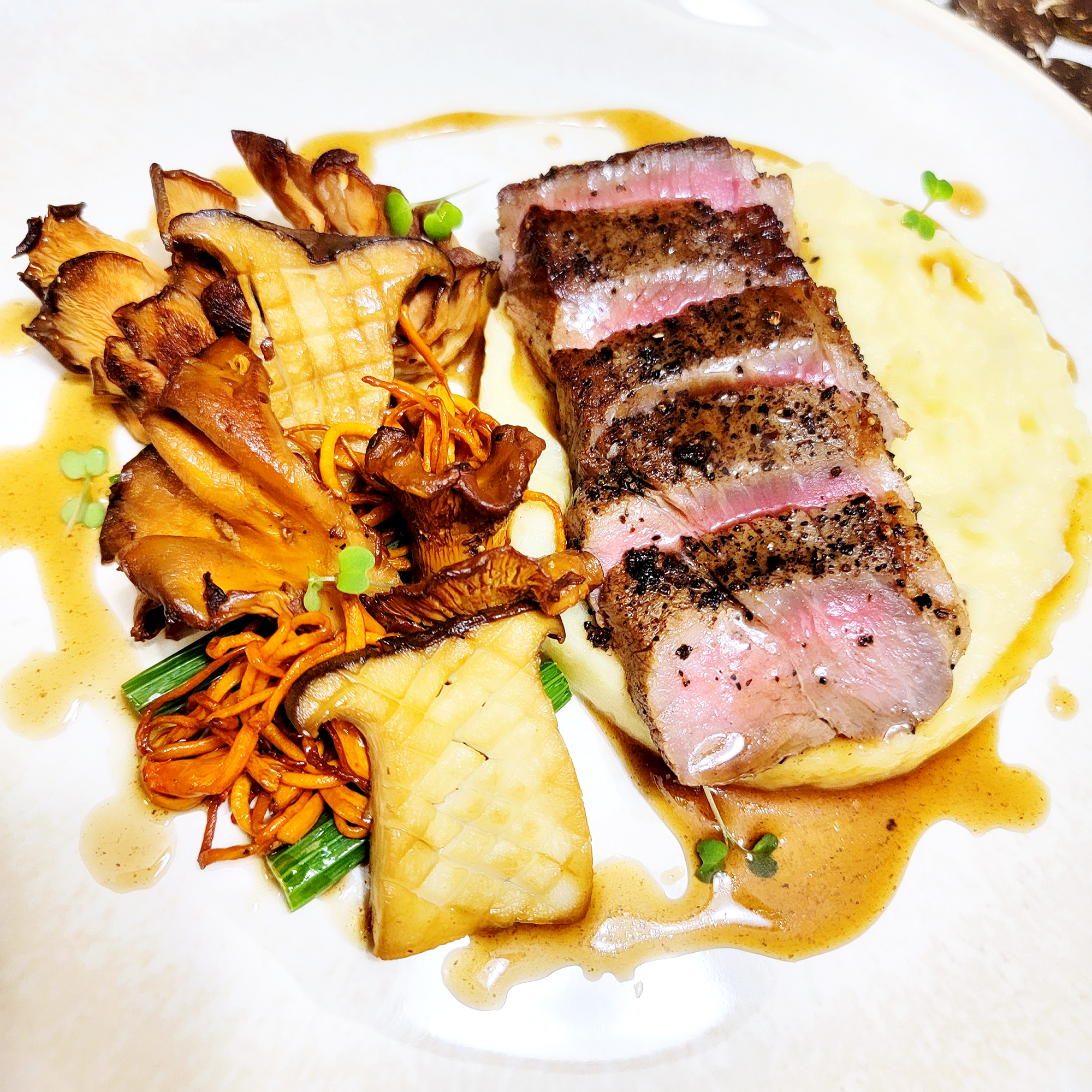 Seared tuna steak with mashed potatoes, grilled vegetables, and sauce.