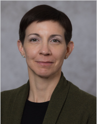 Portrait of a woman with short dark hair in front of a gray background