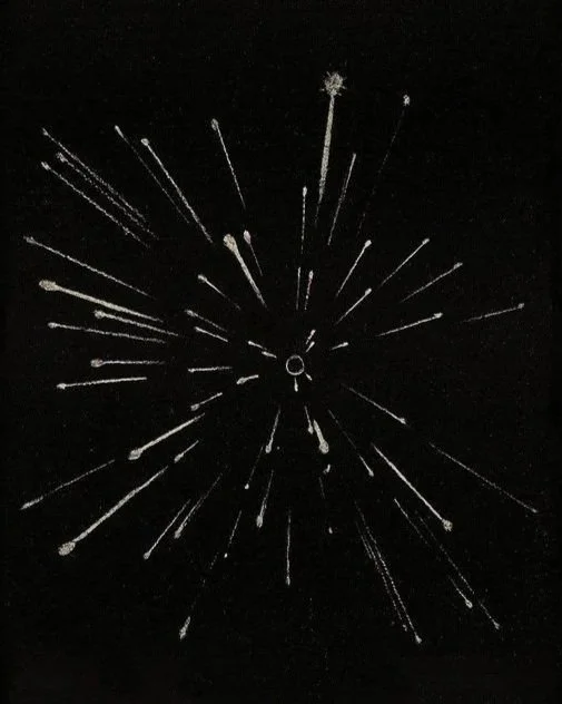 Black and white image of fireworks exploding in the night sky with streaks radiating outward.