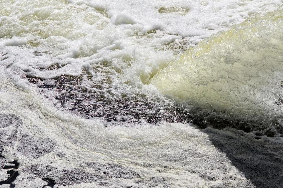 Close-up of turbulent water with foam and bubbles in a river or stream.