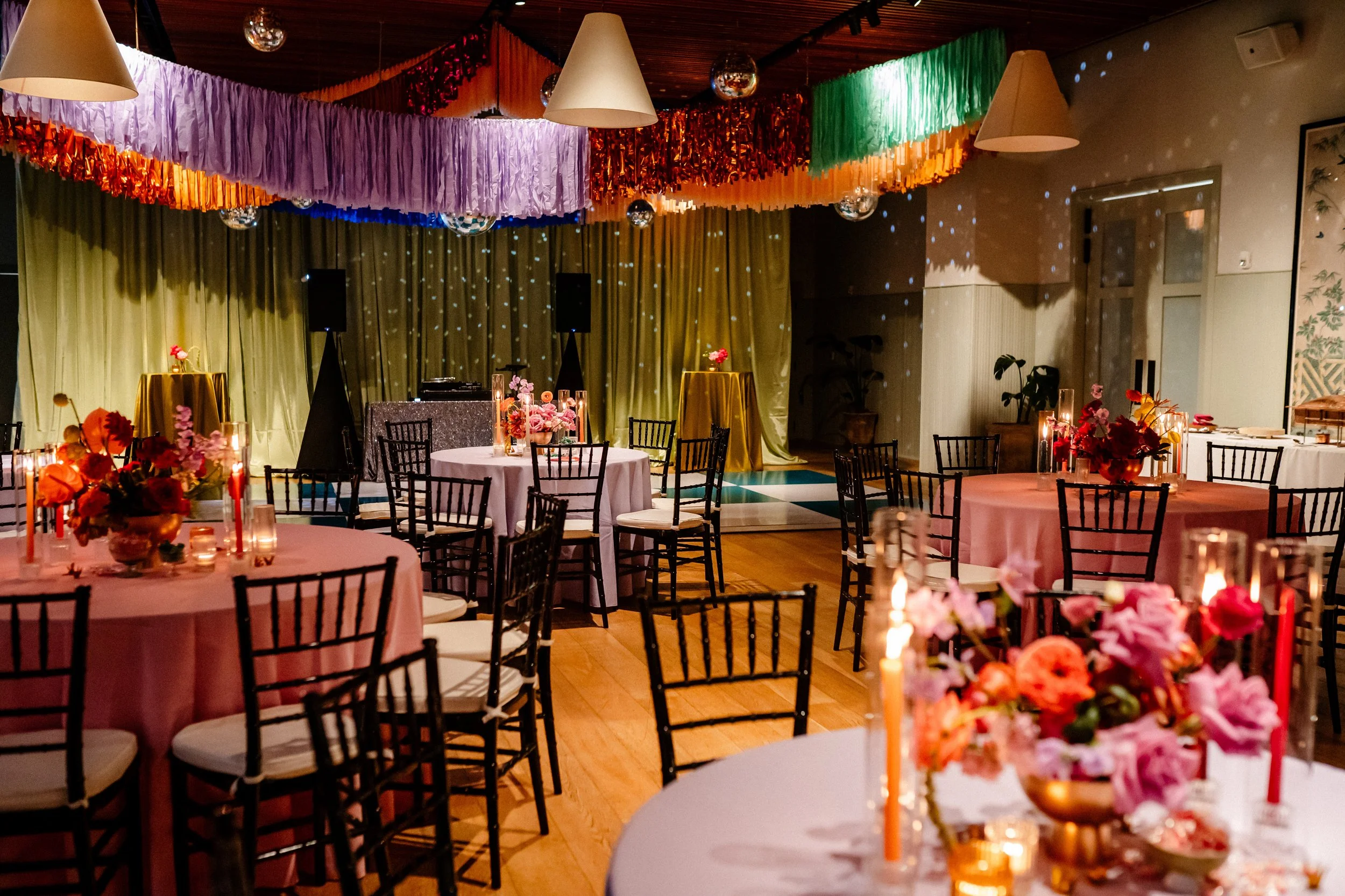 The Hotel St. Vincent in New Orleans, event room with round tables covered in pink and white tablecloths, floral centerpieces, and candles and disco balls.