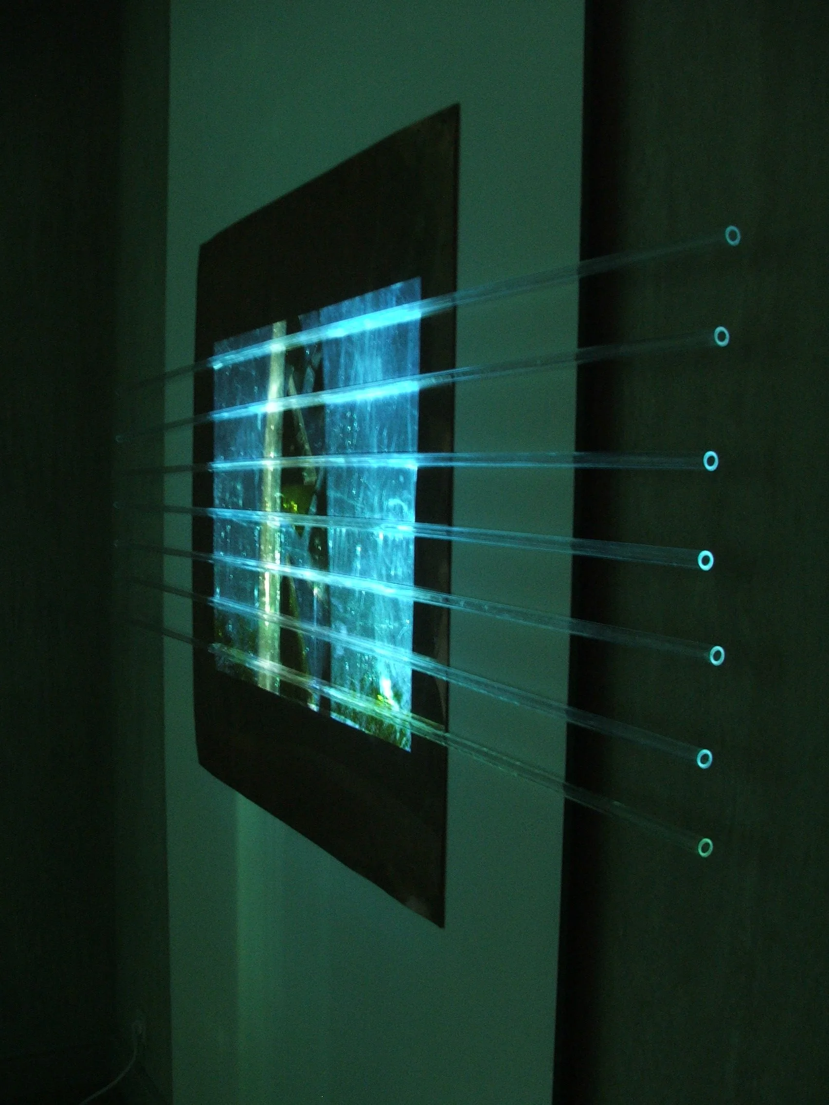 An interactive display with multiple horizontal light strips projecting from a screen in a dark room.