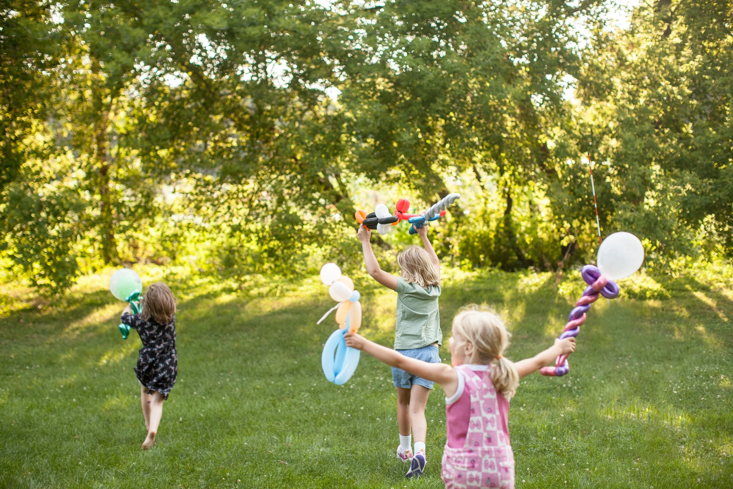 Happy children running and playing with balloon twisted creations