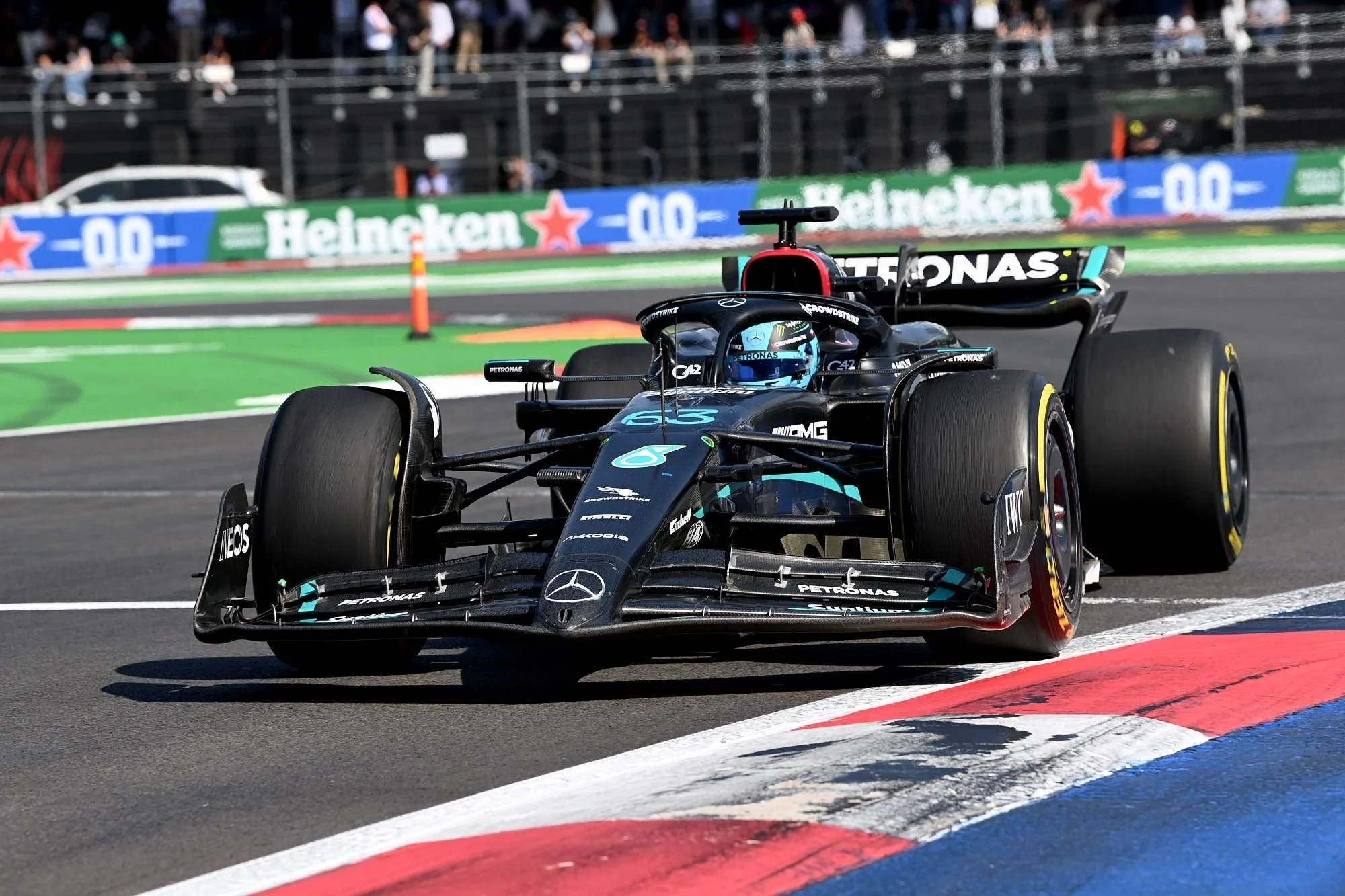 A Mercedes-AMG Petronas Formula 1 car navigating a corner on a racing track during a race, with a crowd and Heineken advertising in the background.