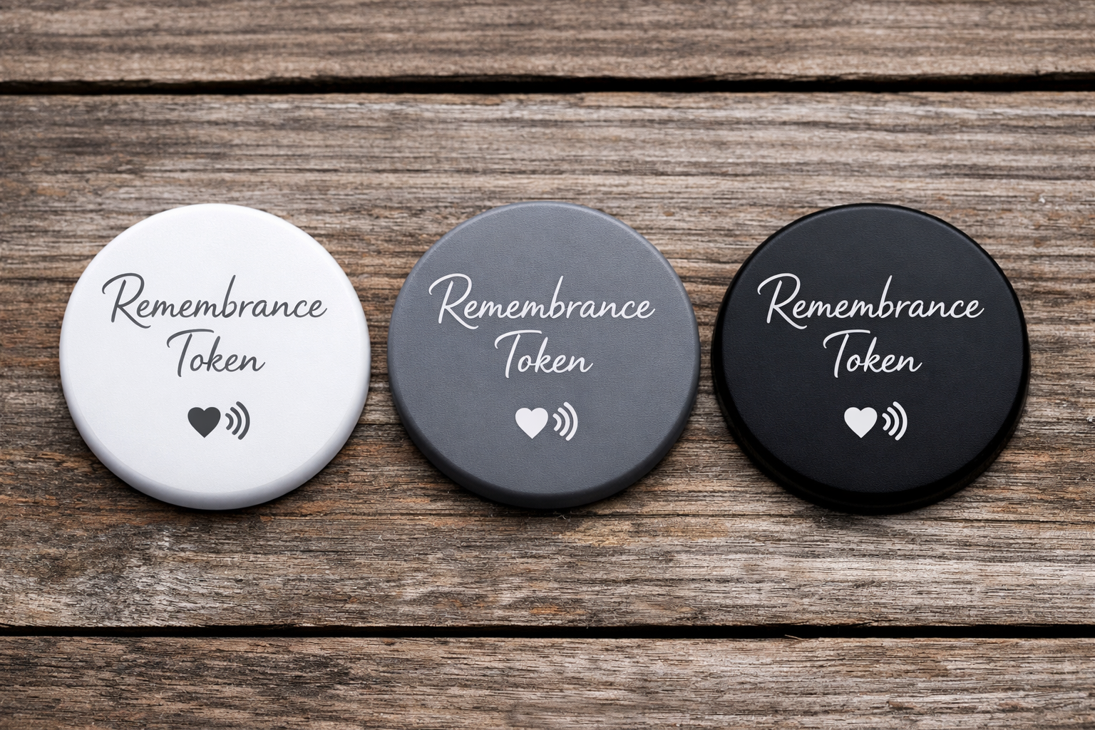 Three circular tokens labeled 'Remembrance Token' with a heart and wireless signal icon, in white, gray, and black, on a wooden surface.