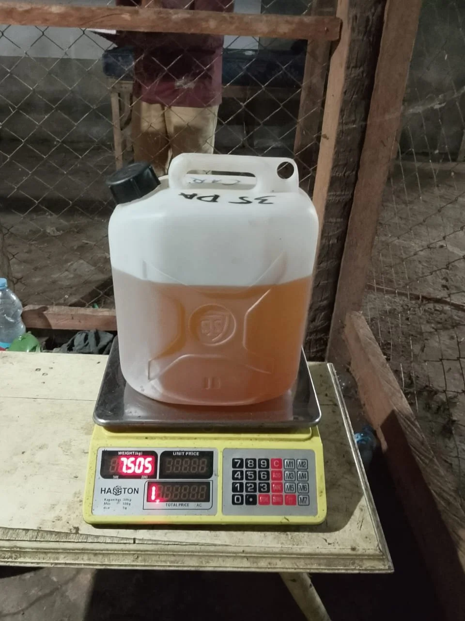 Bukti integritas pengiriman RUMEVA menunjukkan berat bersih 7,505 kg Minyak Nilam murni Sulawesi Utara pada timbangan digital.