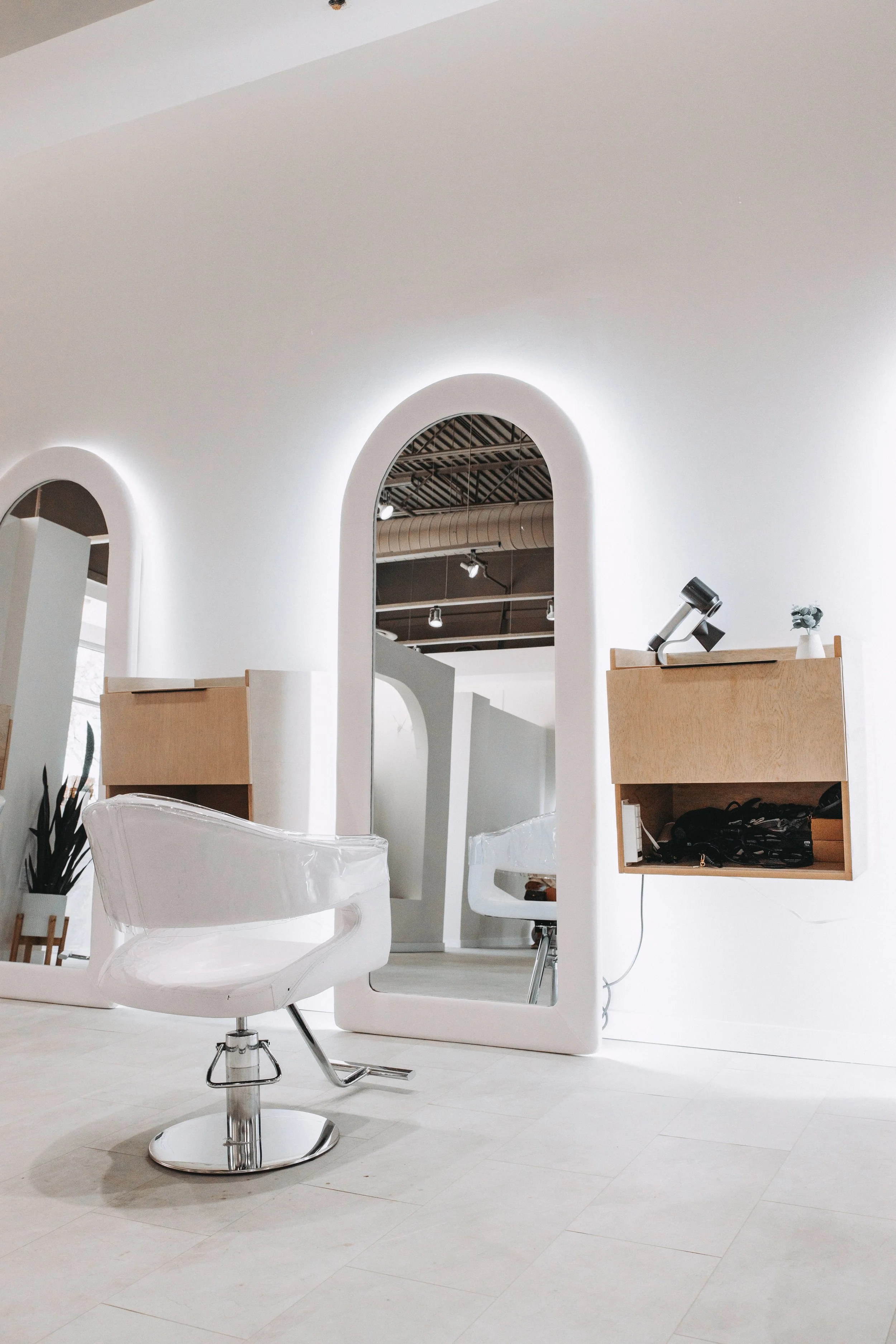 Modern hair salon interior with styling chair, mirror, and white walls.