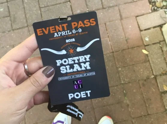 Hand holding a black event pass for Poetry Slam at the University of Texas at Austin, April 6-9, 2016, with a brick sidewalk and leaves in the background.