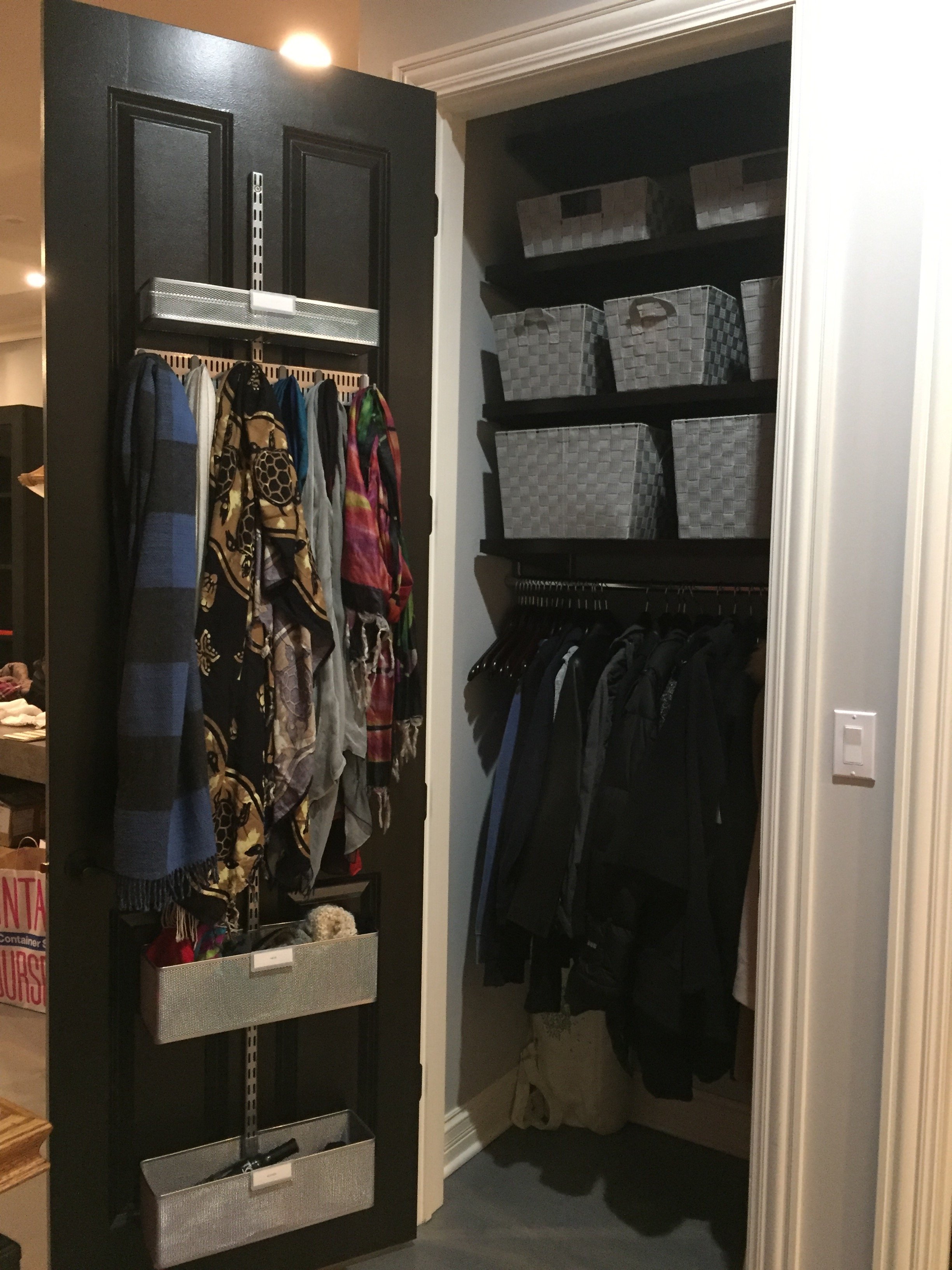 A closet with organized storage, featuring hanging clothes, labeled baskets, and fabric bins on shelves.