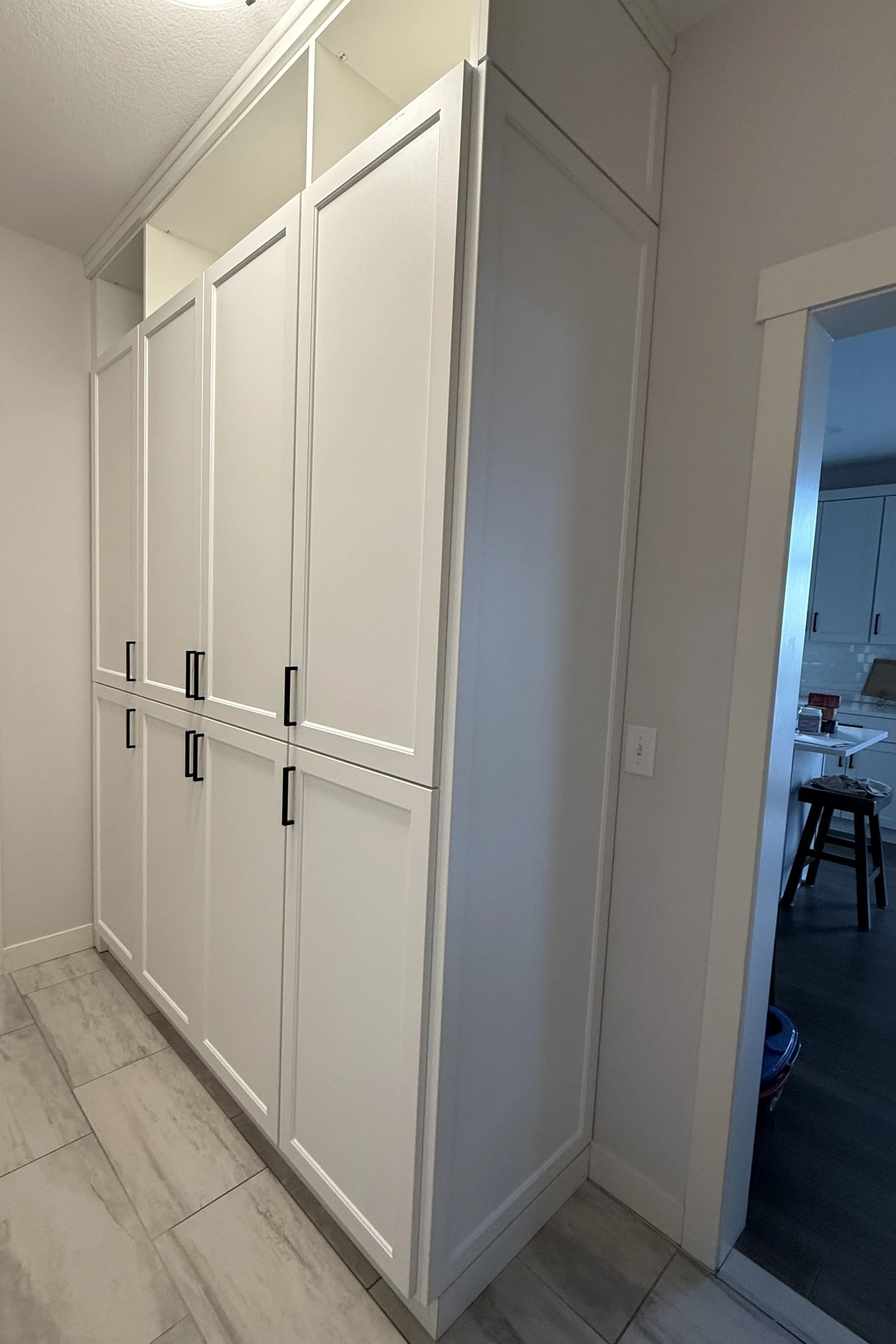 White kitchen cabinets with black handles in a home interior.