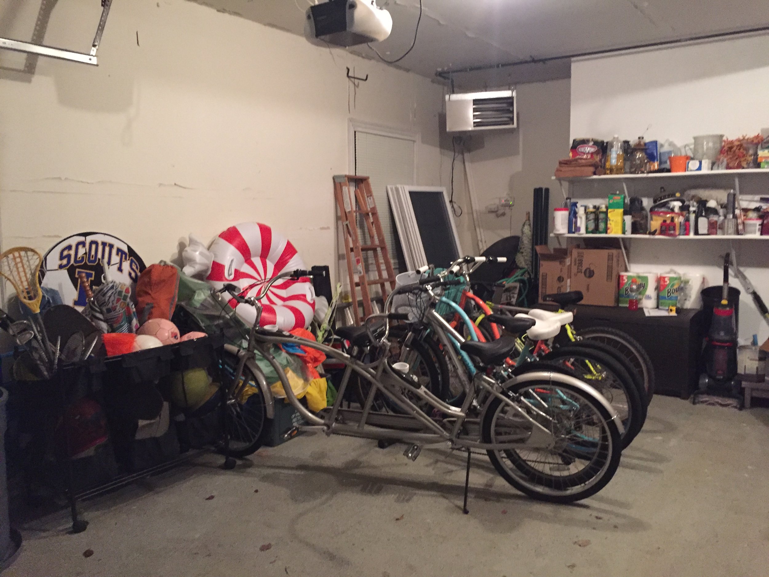 Garage with bicycles, storage shelves, and various household items.