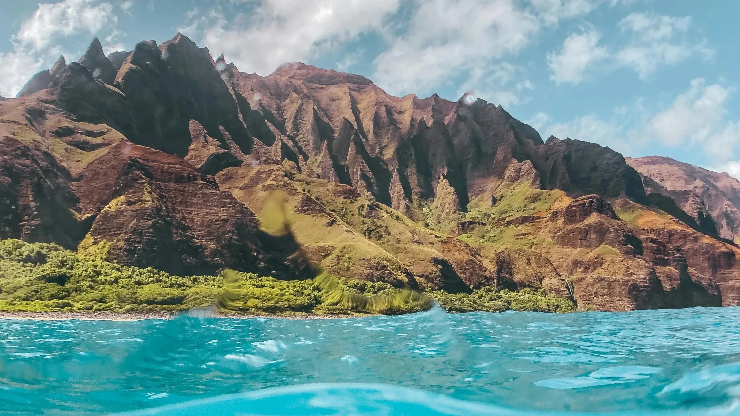 Kauai coastline in the summer with bright blue and aqua green water, beautiful mountain range