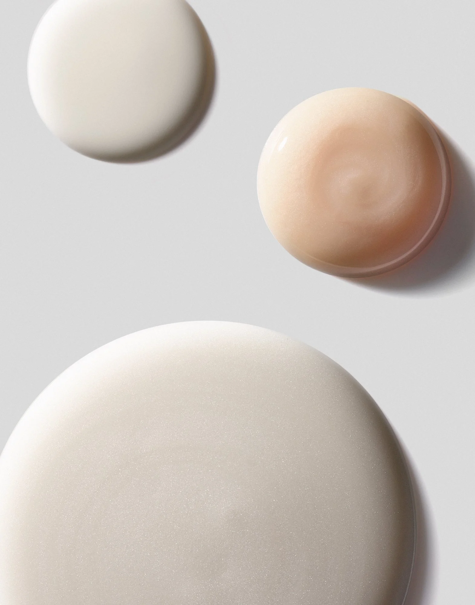 Three SK-II serum textures shown from birds eye macro view against soft gray backdrop