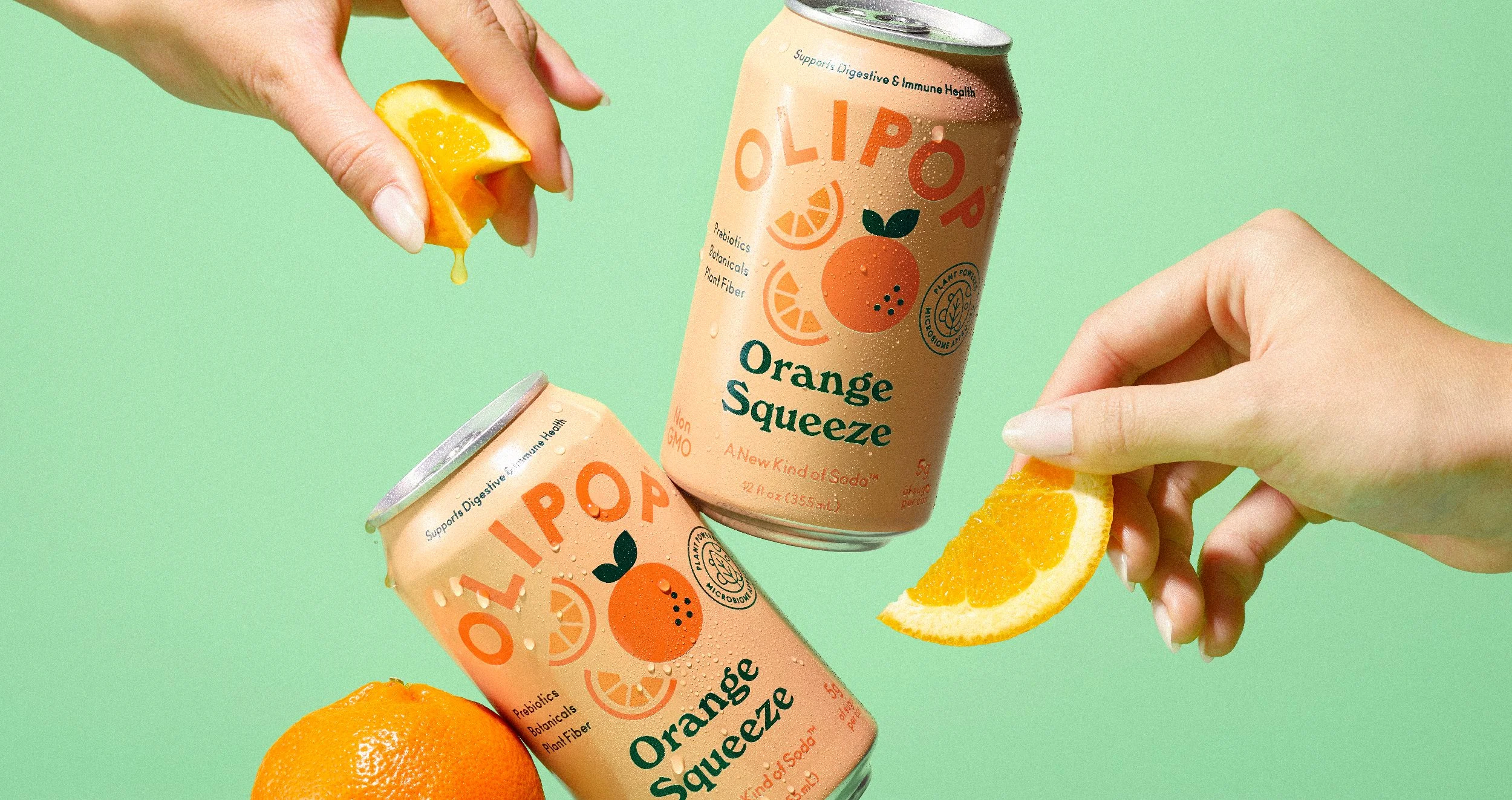 Two hands holding orange slices and cans of Orange Squeeze functional beverage against a green background.