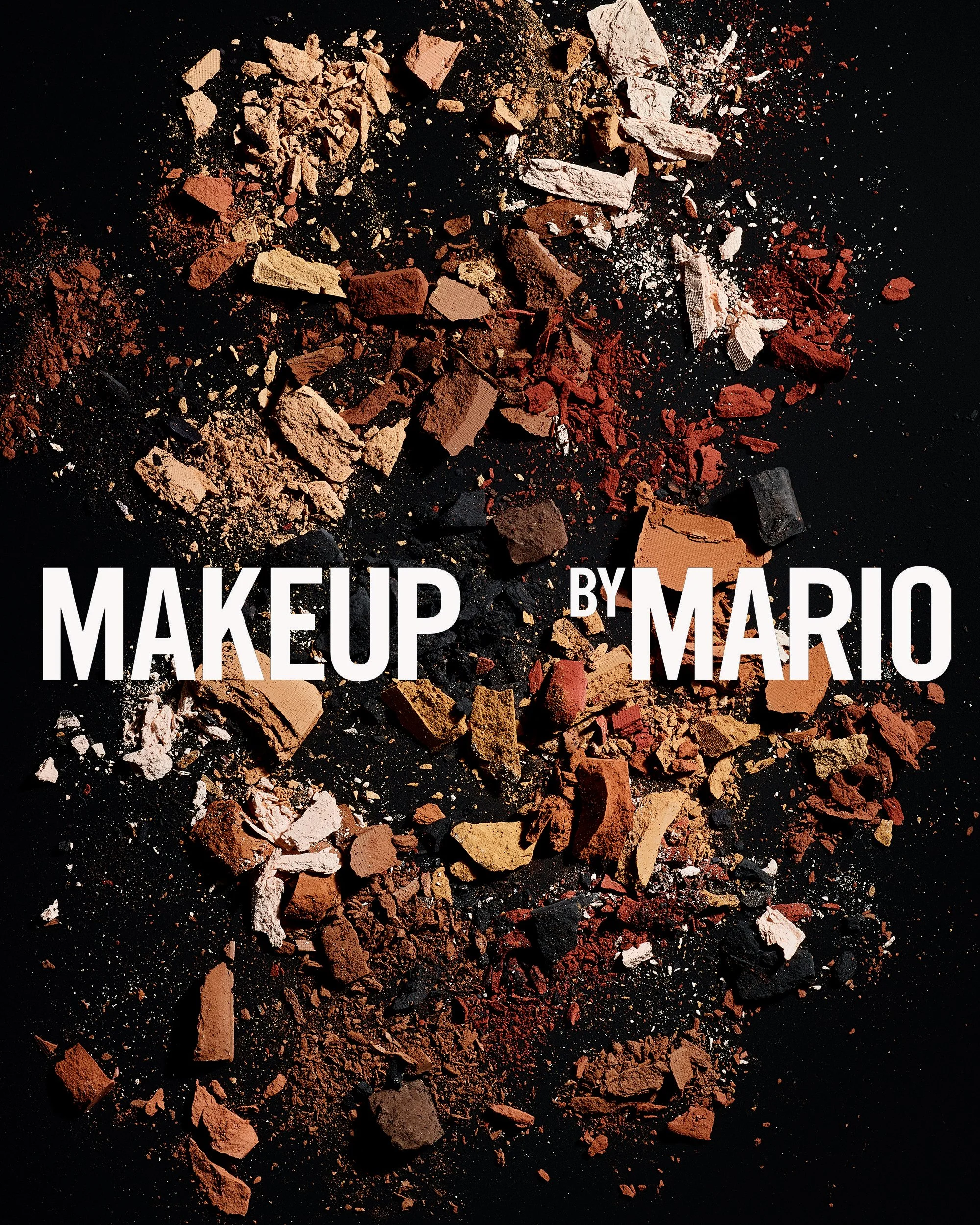 A shade range of matte eye makeup products removed from any packaging are arranged in a stylized composition on a black background with scattered textures filling the frame