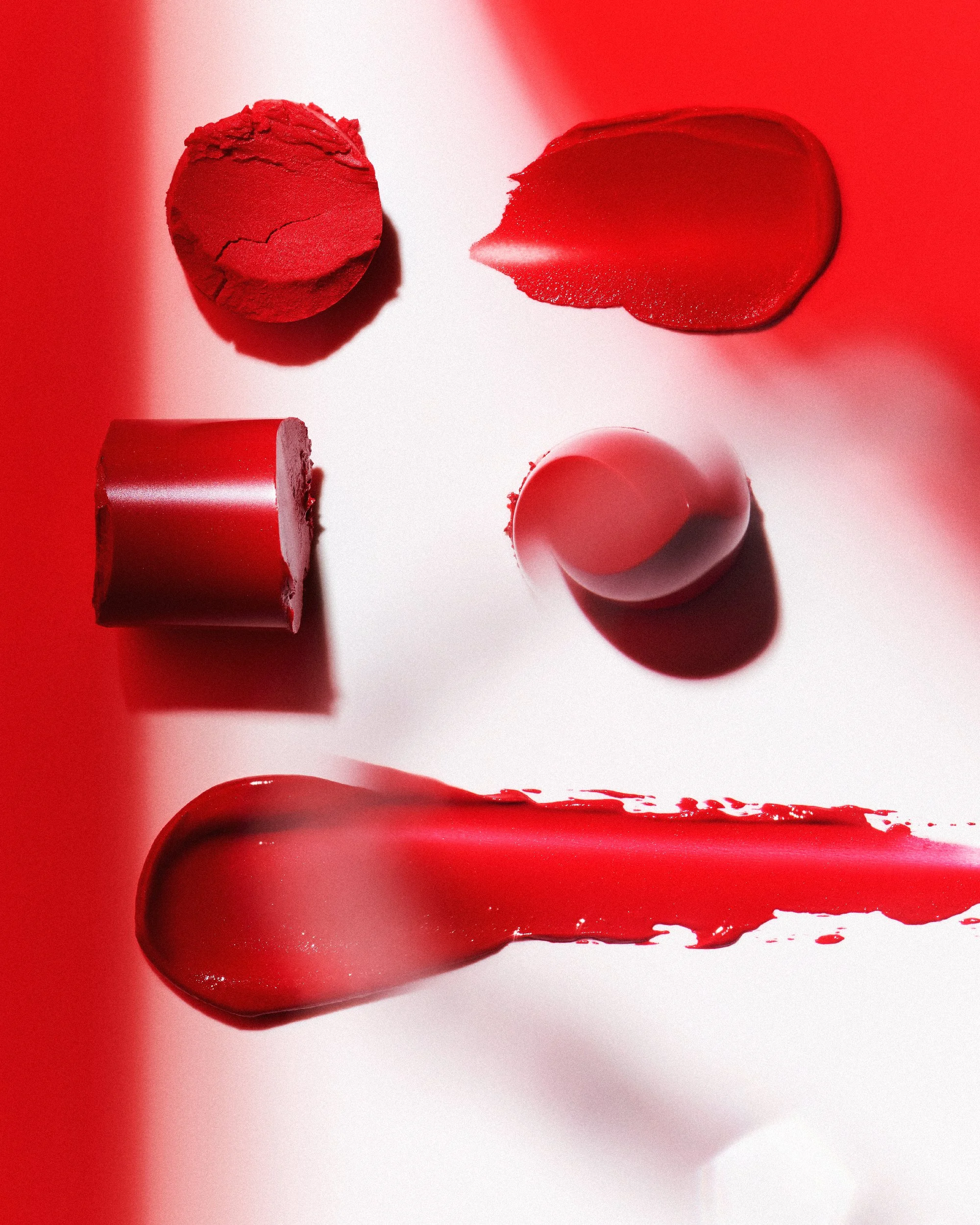 Close-up of three red lipstick tubes, with lipstick swatched on a white surface, creating a visually striking composition.