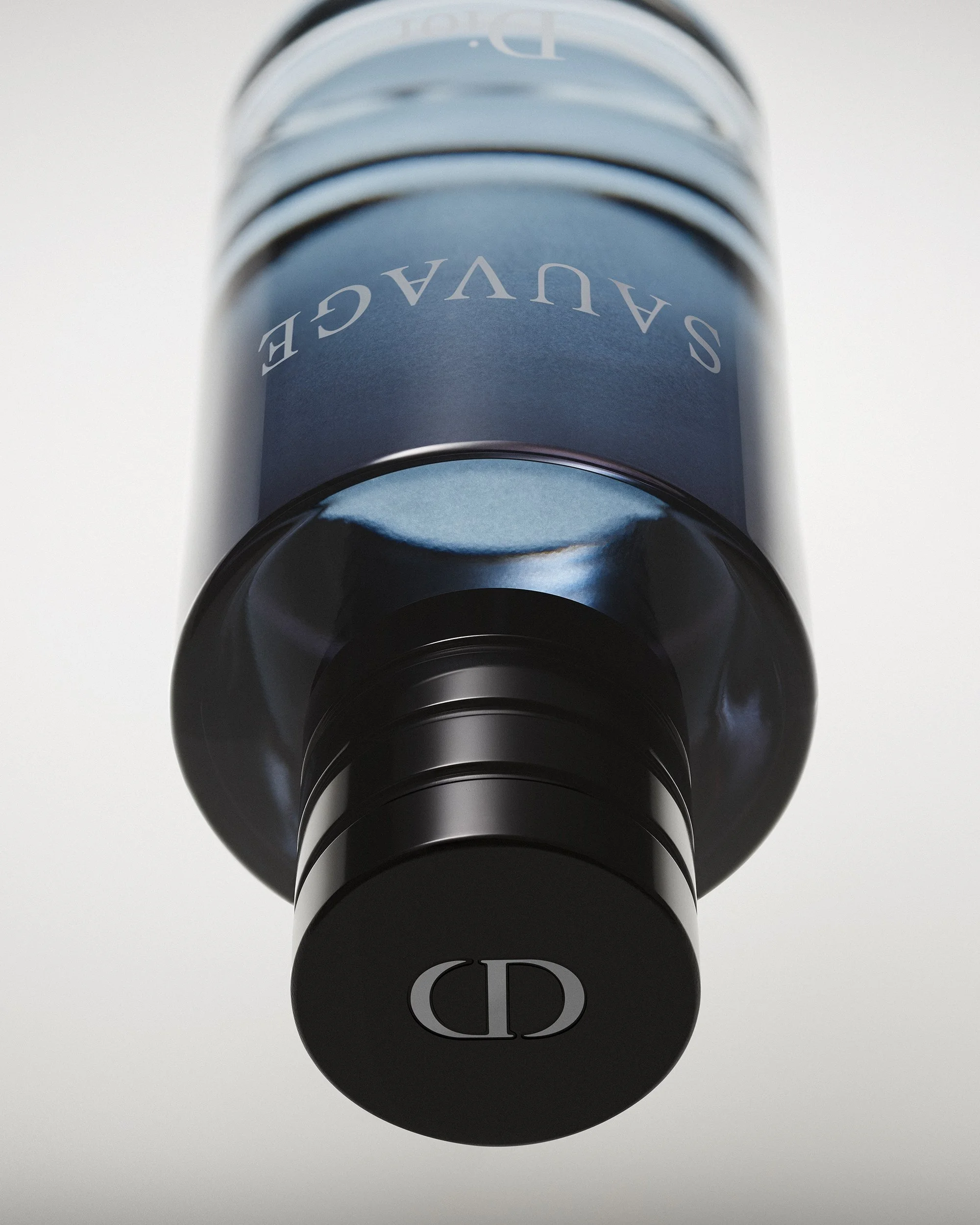 A Dior Sauvage Cologne bottle is shown in a dynamic top-down view with the logo as the main focus. The background is a soft gray gradient