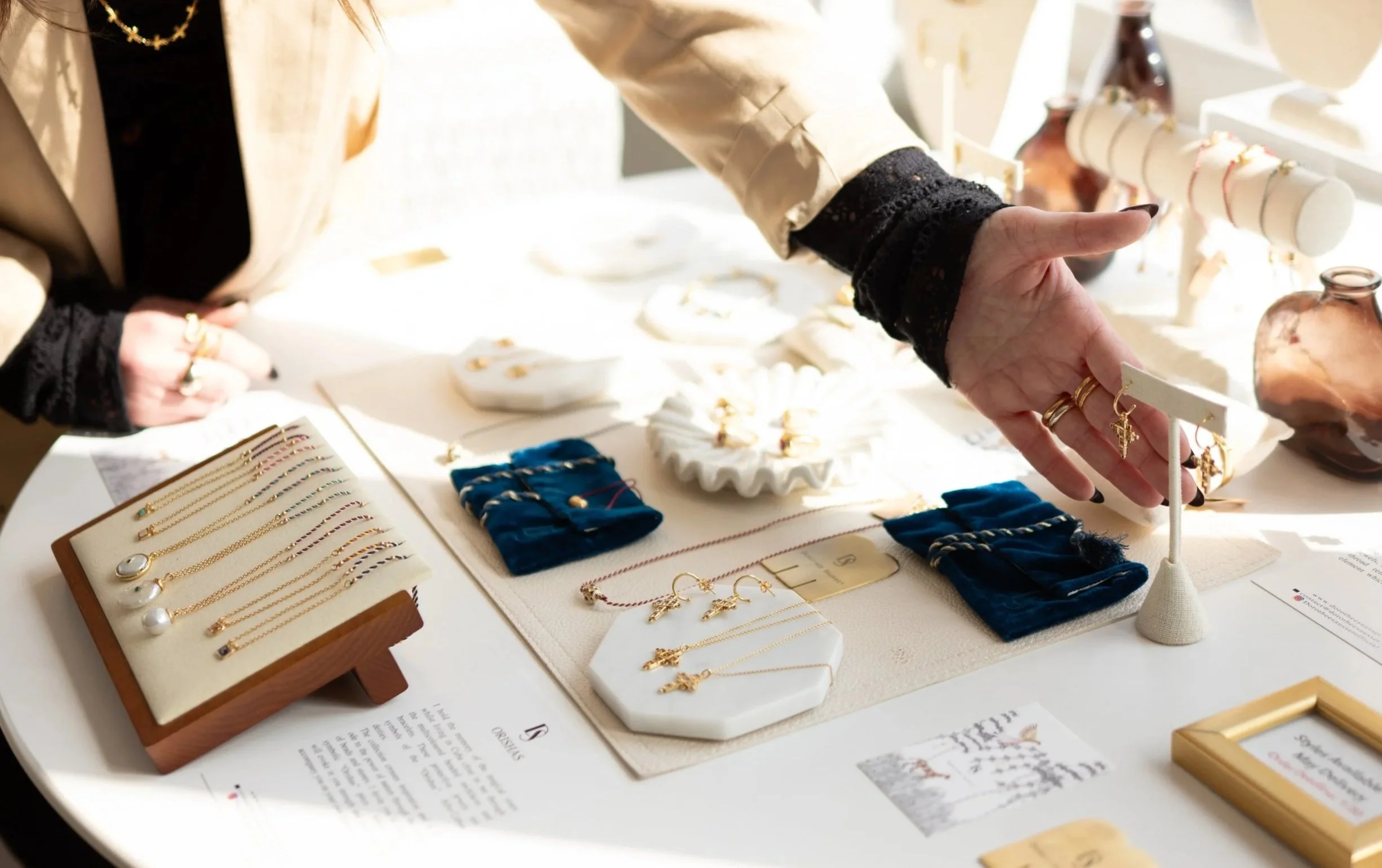 Person browsing jewelry display at a store table with gold necklaces, earrings, and rings.