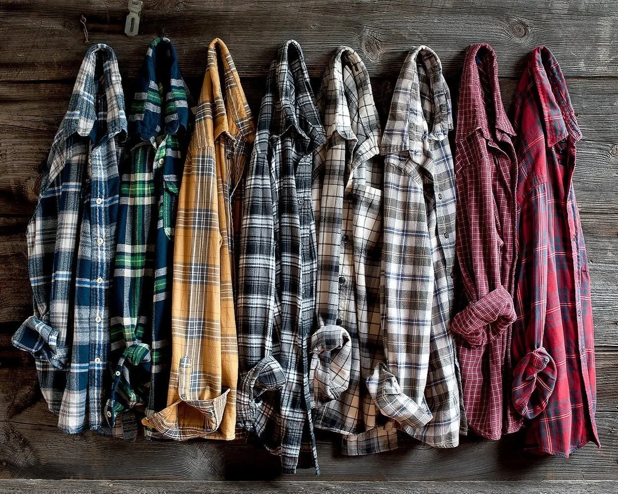 mens flannel shirts hung casually on wood background