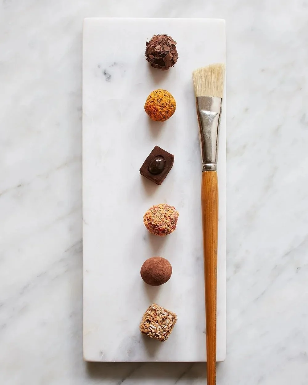 chocolate truffle selection on marble tray with and artists brush